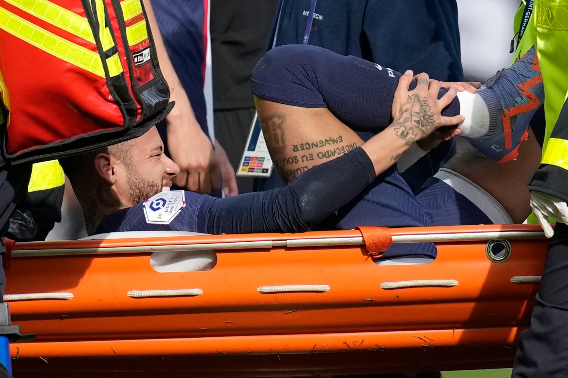 Neymar se toca el tobillo derecho lesionado mientras es retirado en camilla del campo.