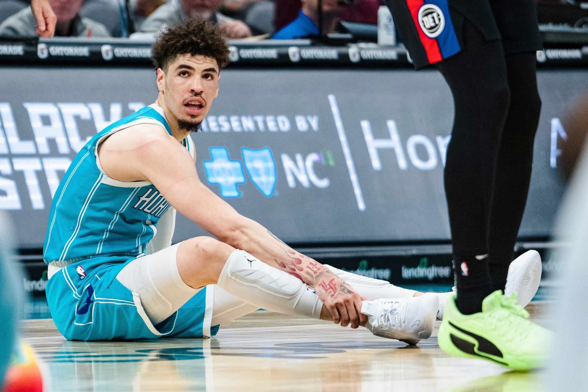 Hornets superstar LaMelo Ball grabs his right ankle after falling awkwardly on Monday night's game against the Pistons.