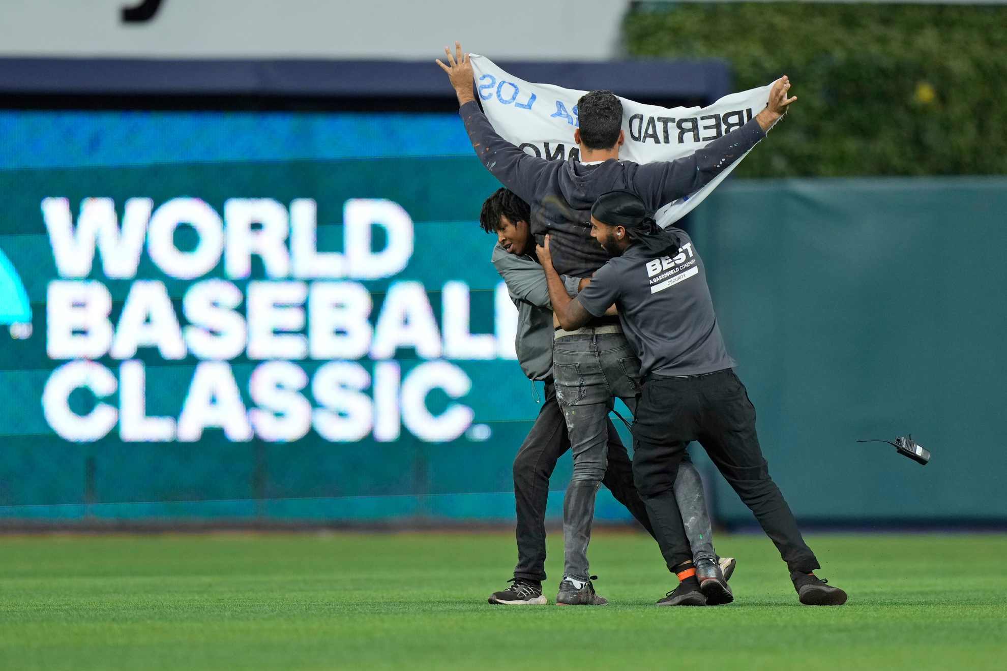 Security guards take out a demonstrator that ran onto the field during the sixth inning of a World Baseball Classic game between Cuba and the U.S.