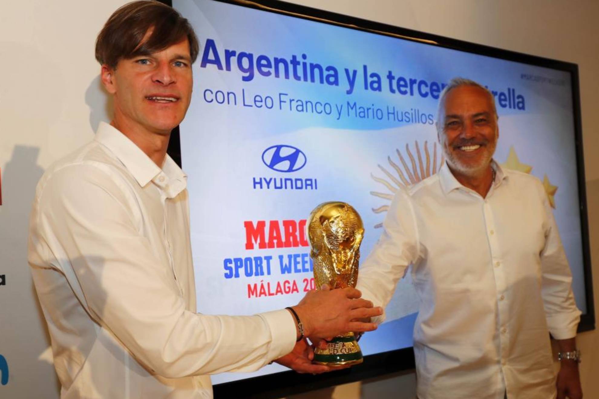 Leo Franco y Mario Husillos posan con una réplica de la Copa del Mundo tras el debate sobre Argentina.