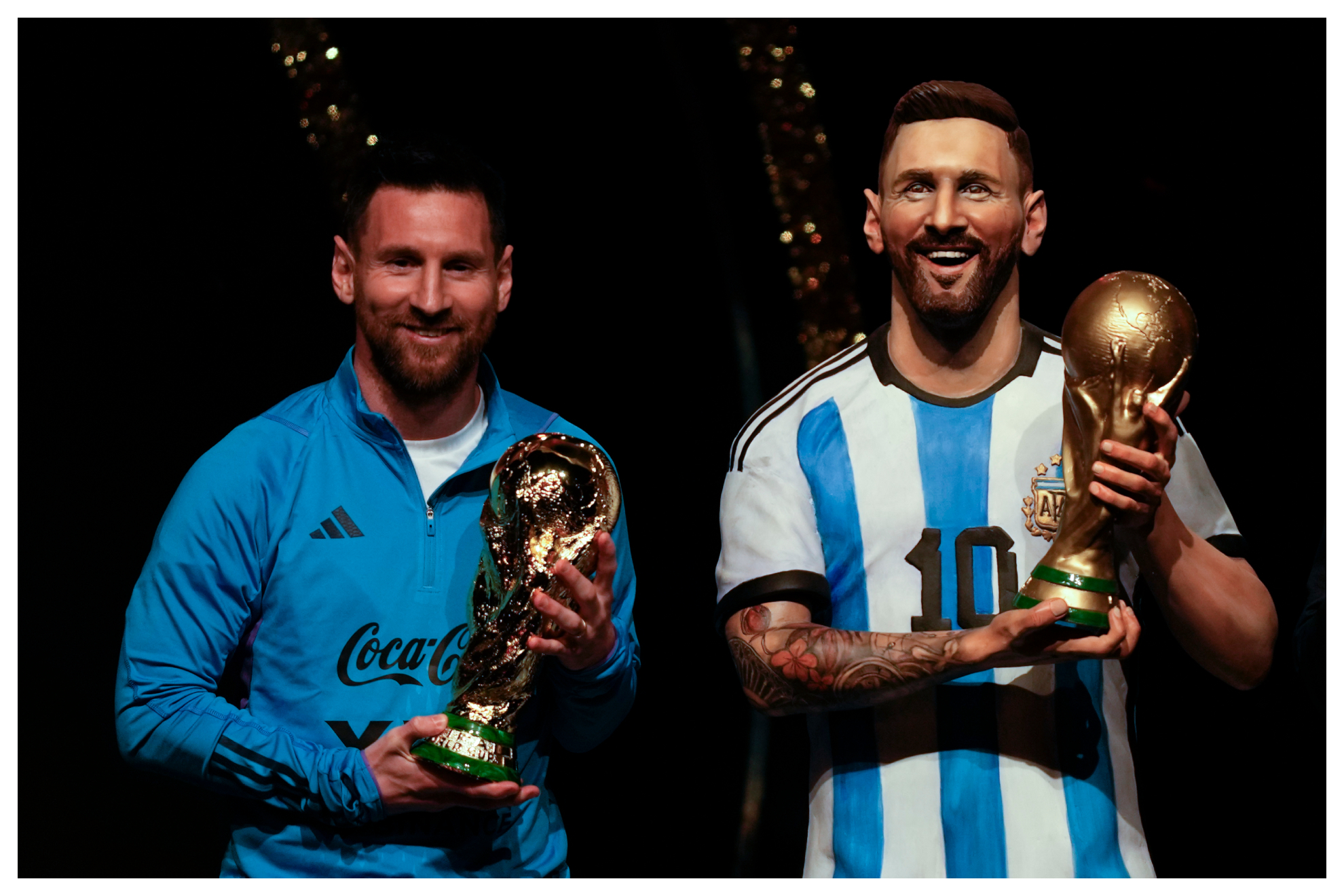 Lionel Messi sostiene una réplica del trofeo de la Copa del Mundo junto a una estatua de él durante una ceremonia en la sede de la CONMEBOL,