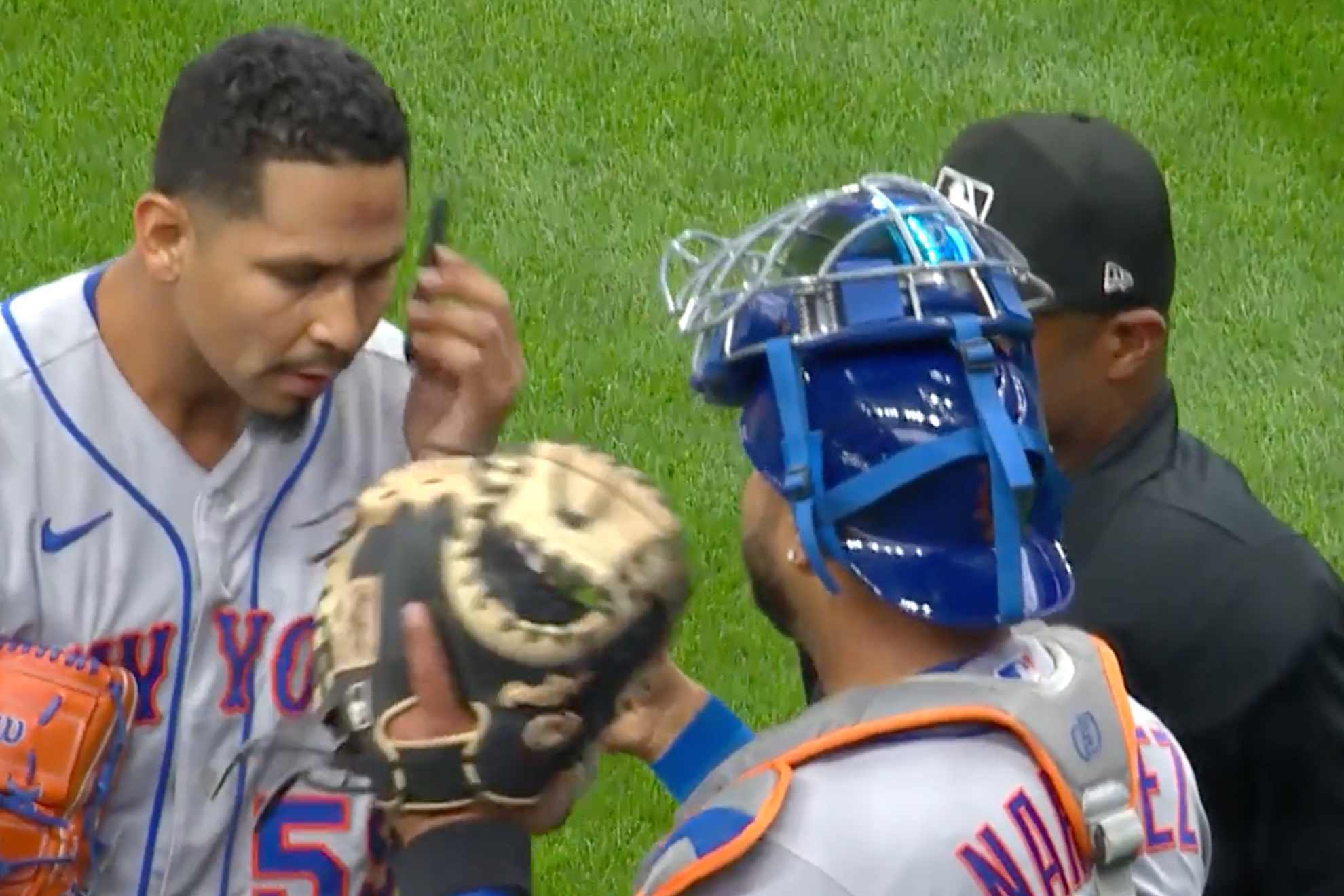Mets pitcher Carlos Carrasco (left) deals with PitchCom issues next to catcher Omar Narvaez and and MLB umpire.