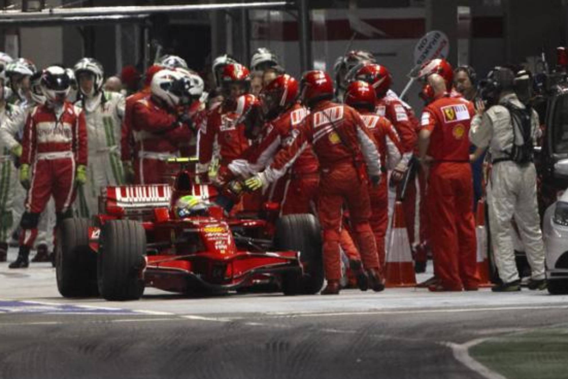 Los mecánicos de Ferrari detienen el coche de Massa, con la manguera puesta, al final del pit..
