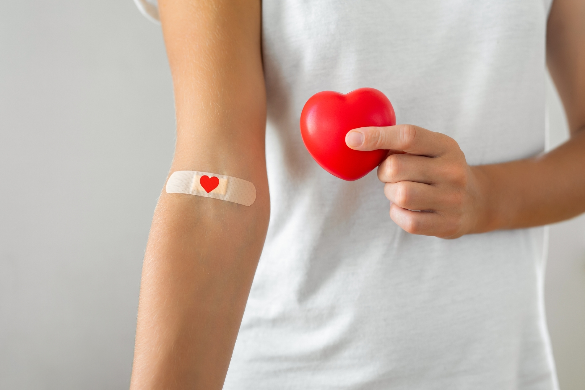 Una persona con una tirita en el brazo sostiene un corazn de goma.