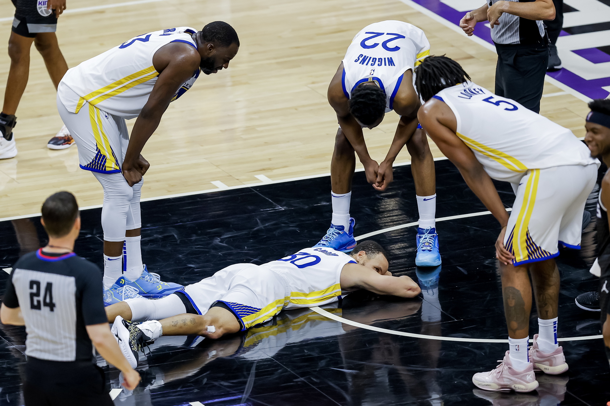Curry, tendido en el suelo tras una canasta, rodeado por sus compañeros.