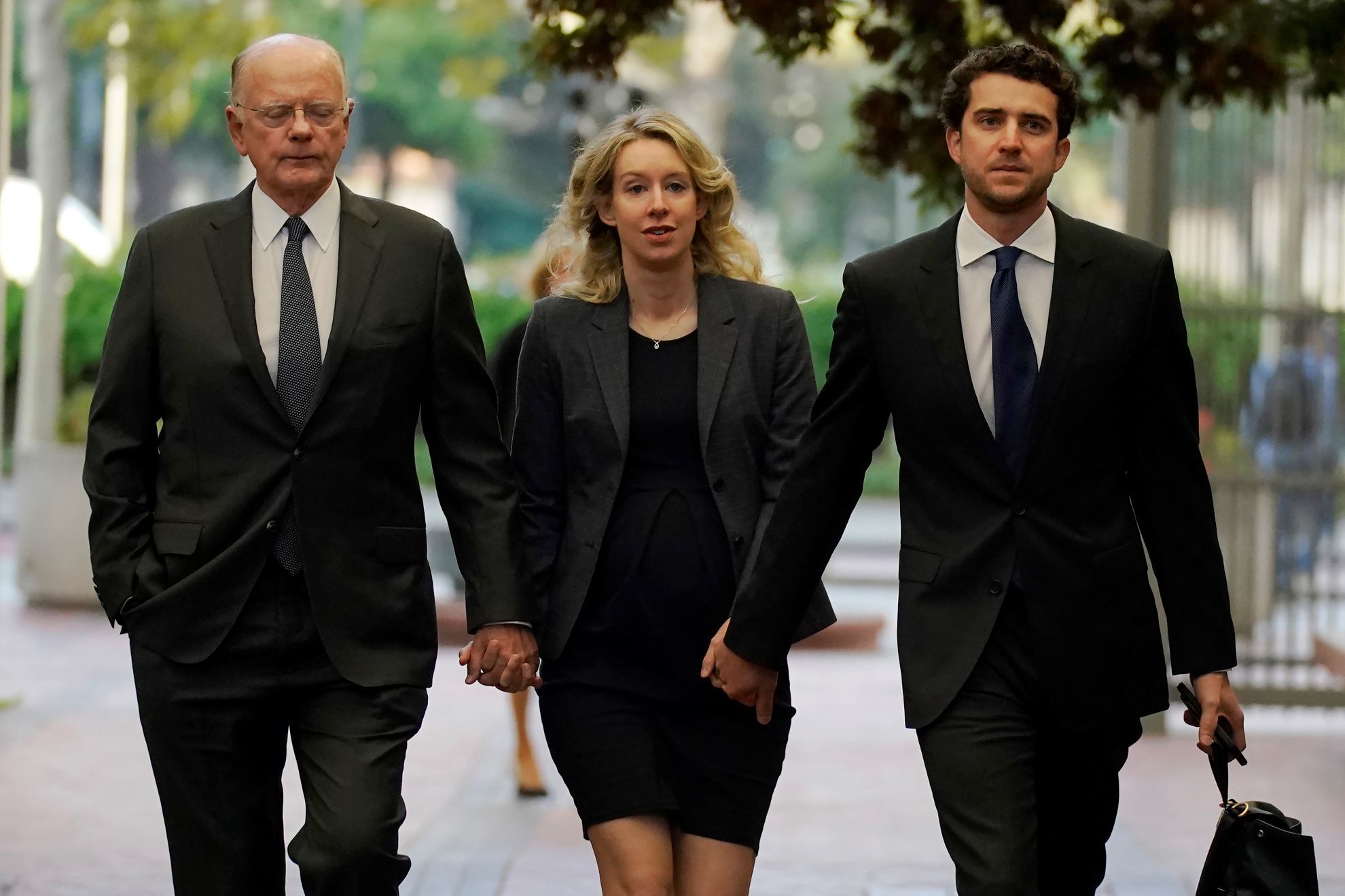 Former Theranos CEO Elizabeth Holmes, center, arrives at federal court with her father, Christian Holmes IV, left, and partner, Billy Evans.
