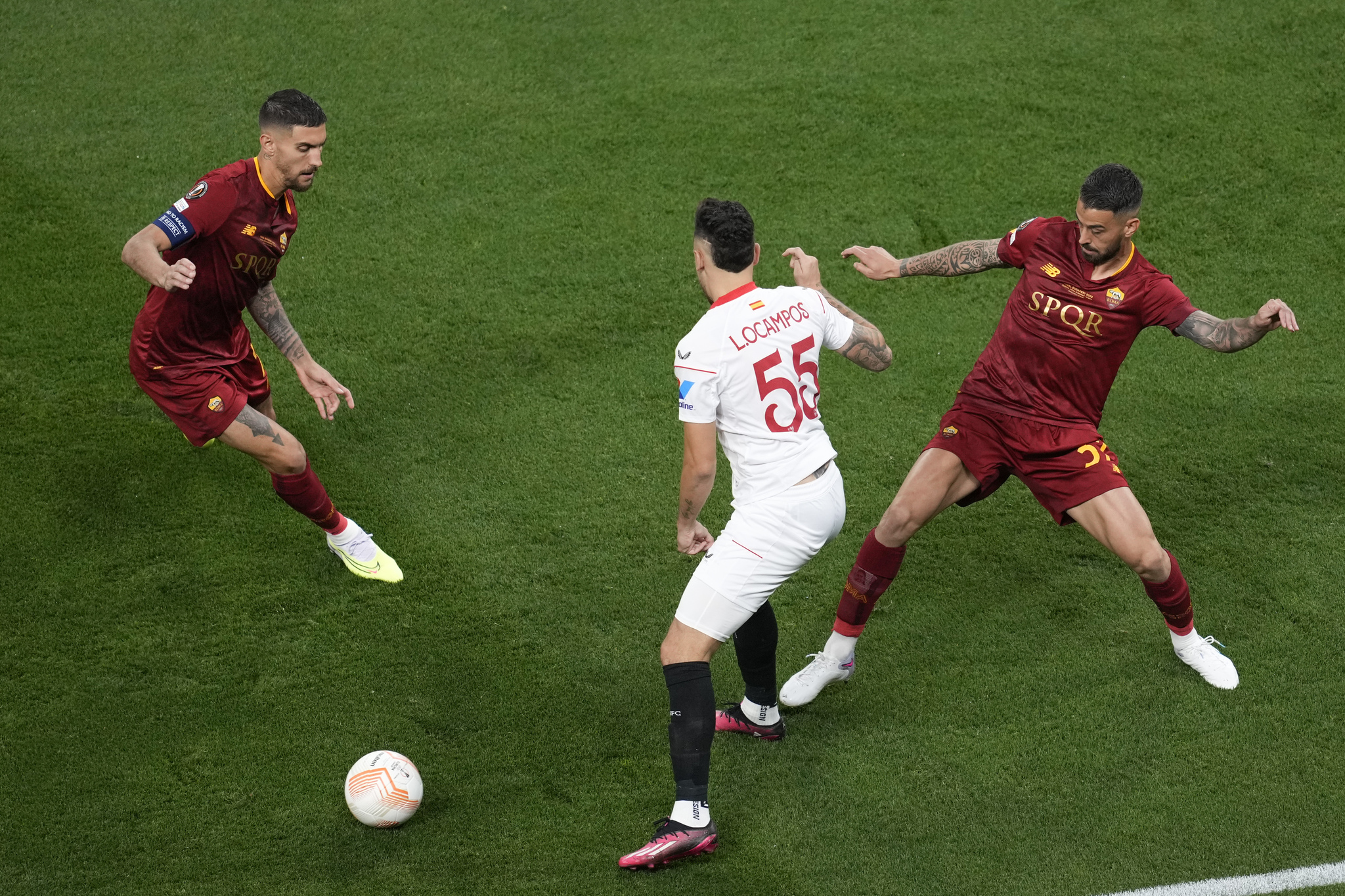 Sevilla's Lucas Ocampos, center, is challenged by Roma's Lorenzo Pellegrini, left, and Leonardo Spinazzola, uring the  lt;HIT gt;Europa lt;/HIT gt;  lt;HIT gt;League lt;/HIT gt; final soccer match between Sevilla and Roma, at the Puskas Arena in Budapest, Hungary, Wednesday, May 31, 2023. (AP Photo/Darko Vojinovic)