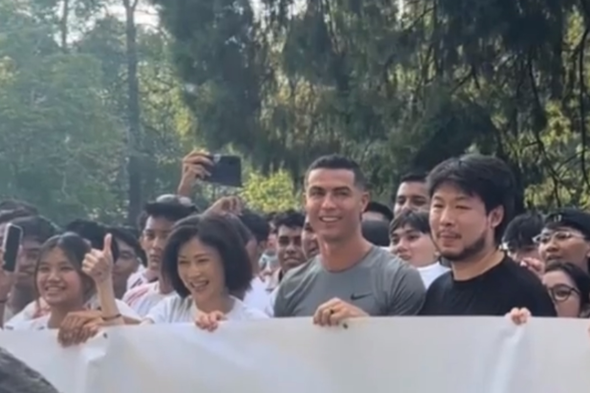 Momento en el que Cristiano Ronaldo posa ante el árbol Peter Lim, junto a Kiat.
