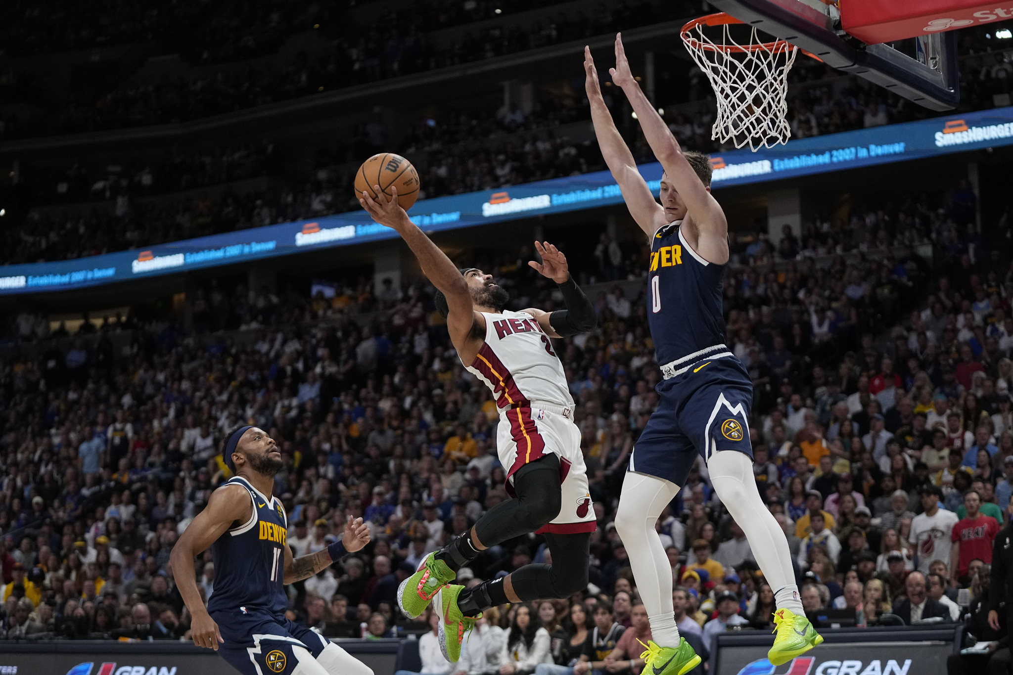 Miami Heat guard Gabe Vincent, center, shoots while defended by  lt;HIT gt;Denver lt;/HIT gt; Nuggets guard Christian Braun, right, during the first half of Game 2 of basketball's NBA Finals, Sunday, June 4, 2023, in  lt;HIT gt;Denver lt;/HIT gt;. (AP Photo/Mark J. Terrill)