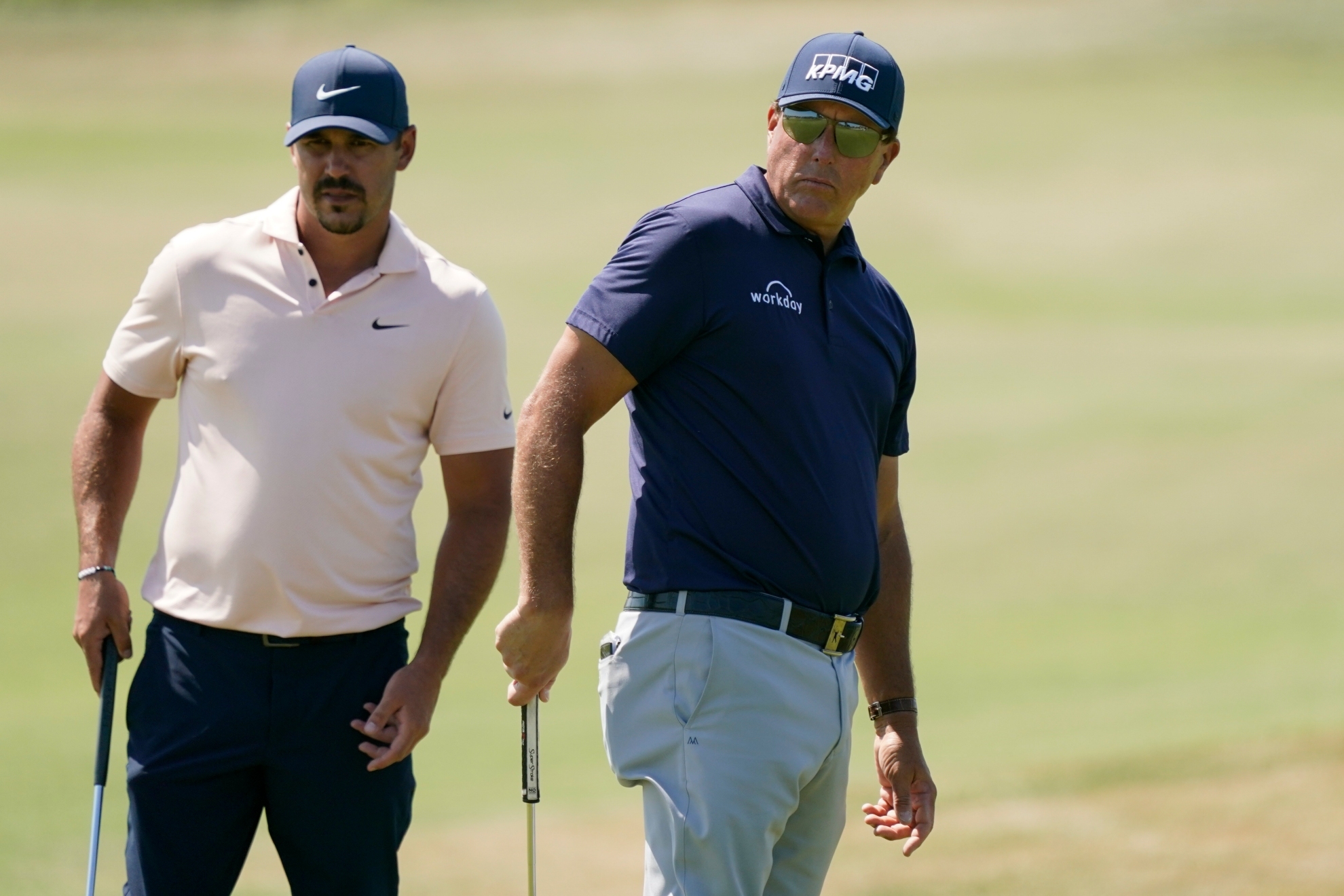 Brooks Koepka and Phil Mickelson playing golf.