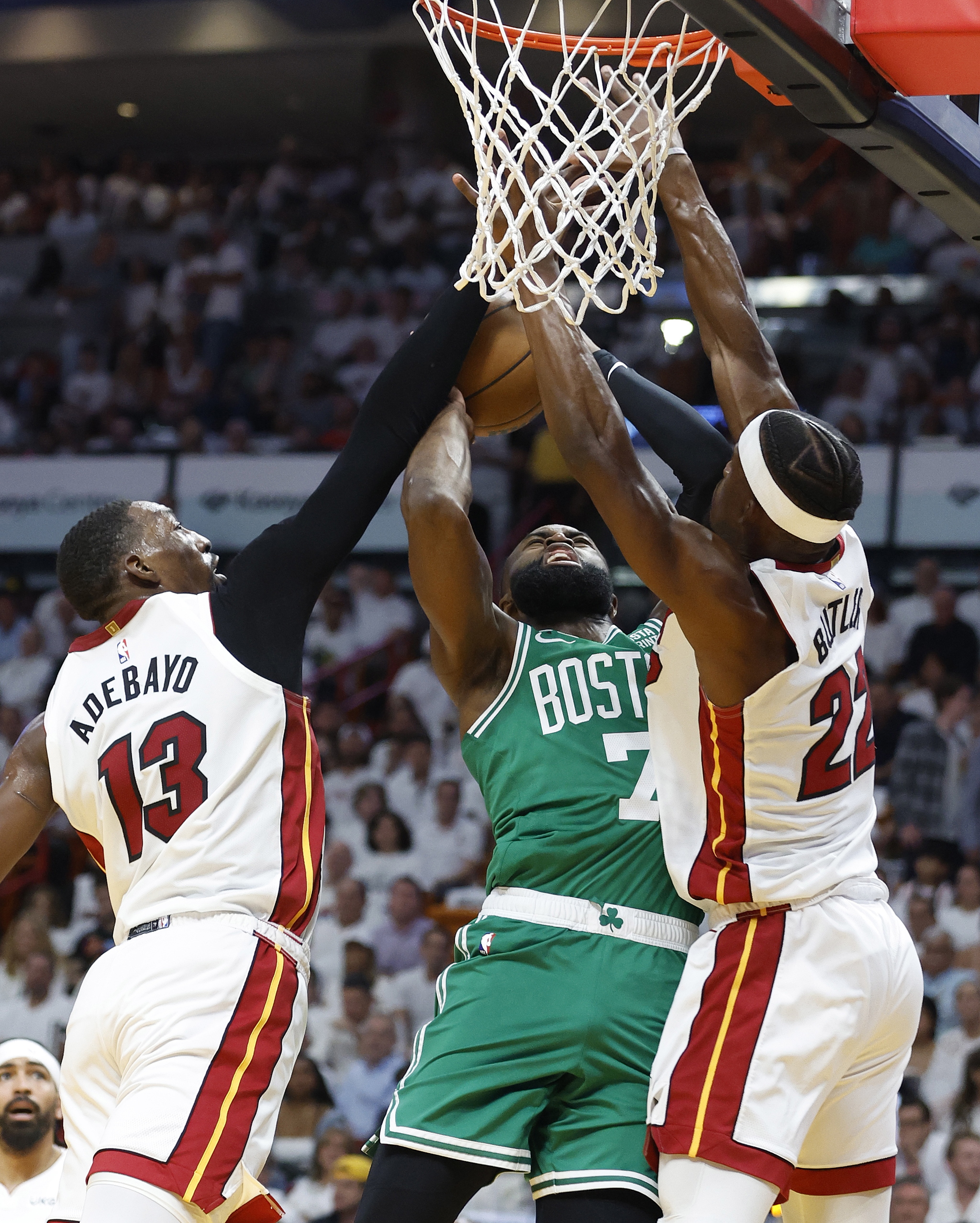 Miami Heat center Bam Adebayo (L) and forward Jimmy Butler (R) block Boston Celtics guard Jaylen Brown (C)