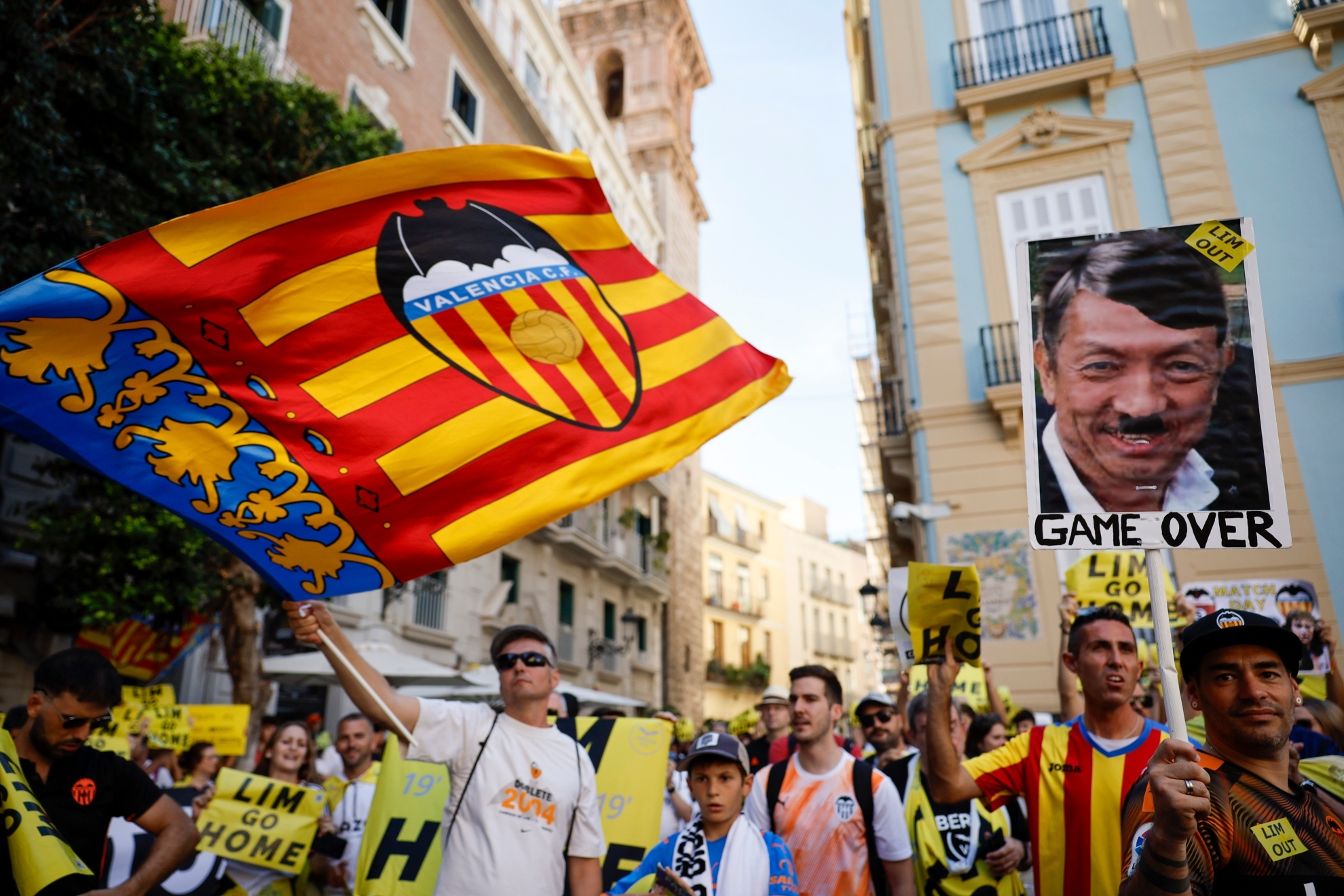 Manifestantes con banderas y escudos del Valencia y una foto trucada de Peter Lim.