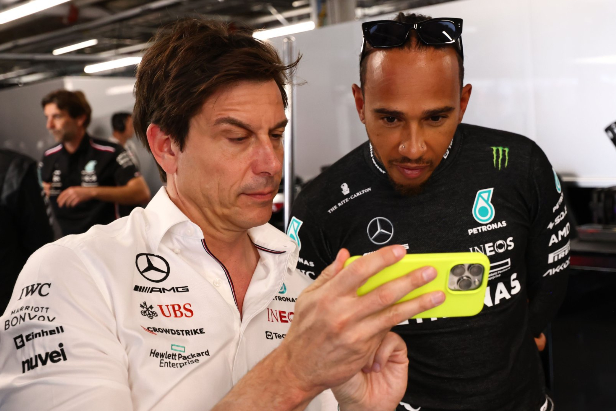 Hamilton presta atención a un detalle que le enseña Wolff a través de su móvil.