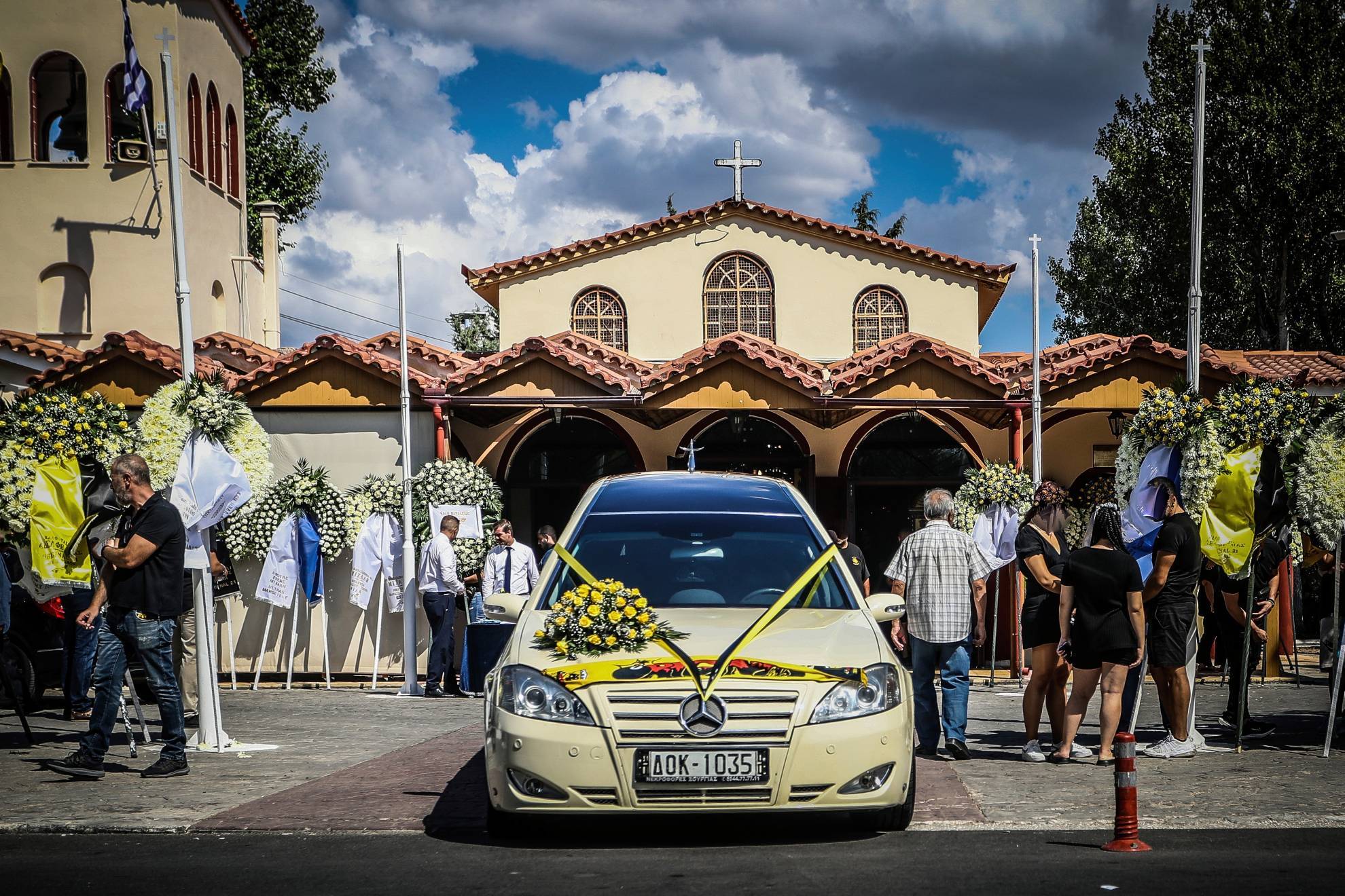 People stand outside a church during the funeral of AEK Athens fan Michalis Katsouris