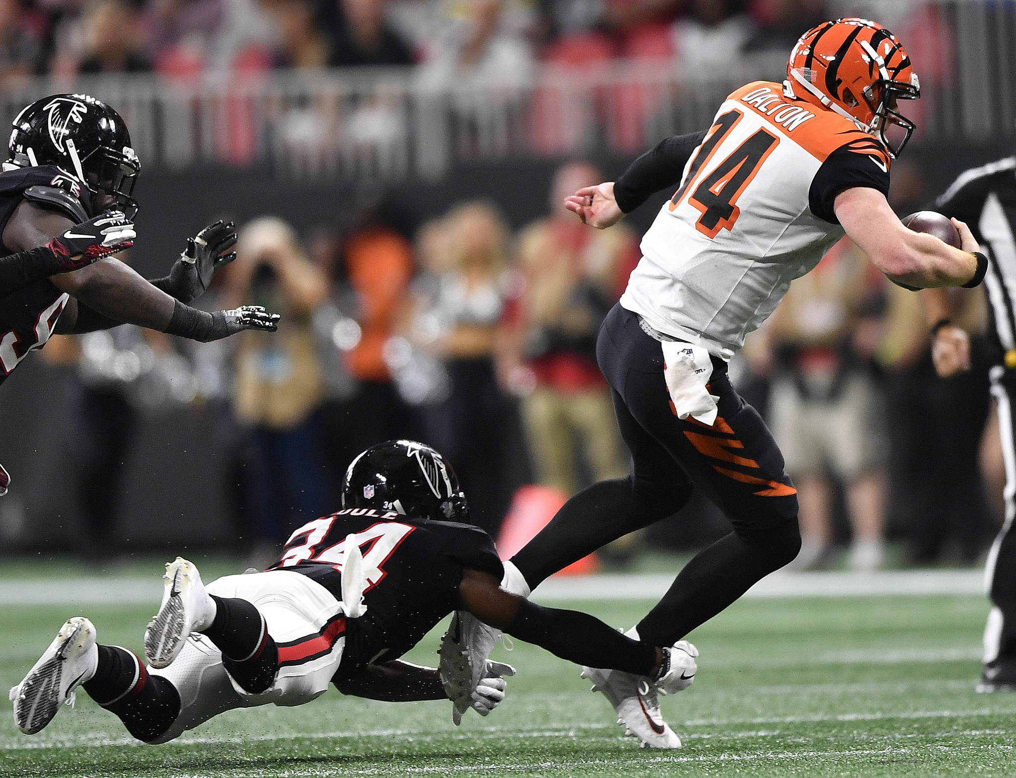 Cincinnati Bengals quarterback is tripped up by Atlanta Falcons cornerback during the second half of an NFL football game.