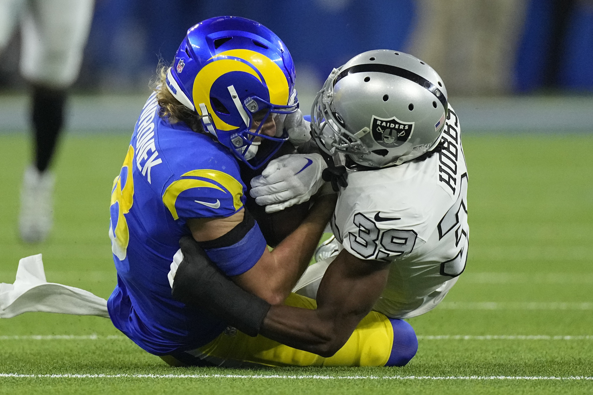 Los Angeles Rams wide receiver holds on to a reception as he is hauled down by Las Vegas Raiders cornerback.
