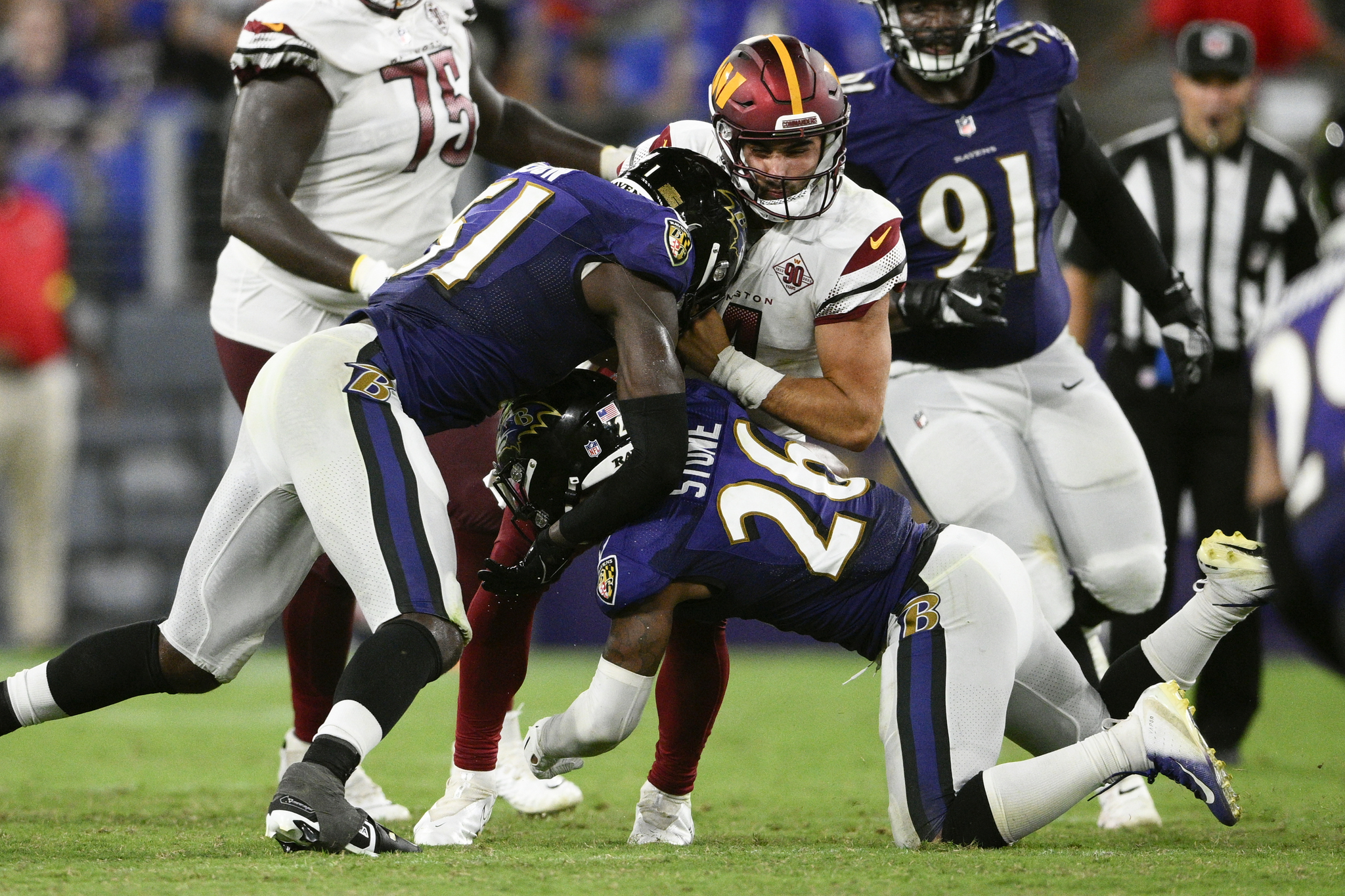 Washington Commanders quarterback is sacked by Baltimore Ravens players.