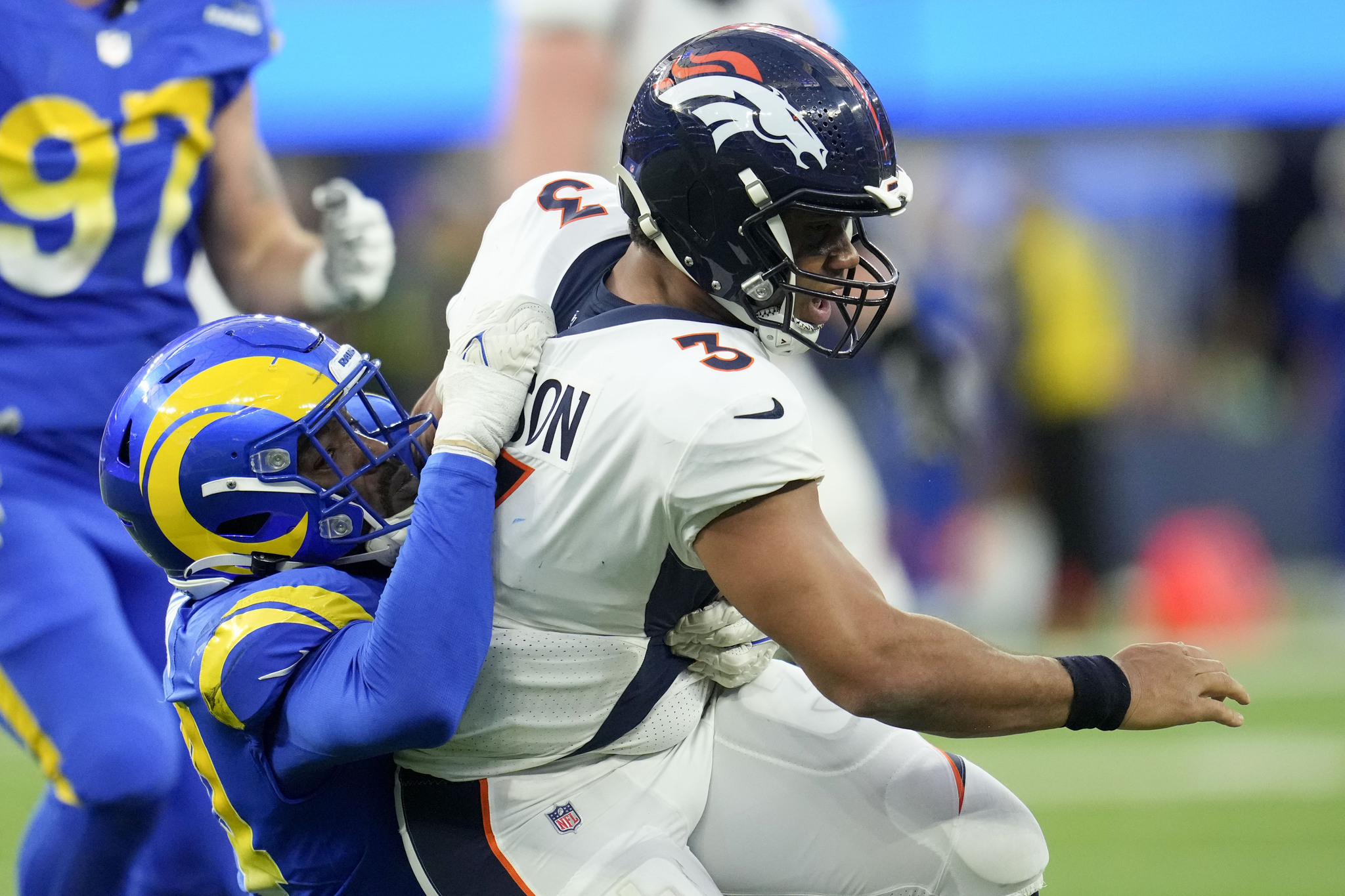 Denver Broncos quarterback is tackled by Los Angeles Rams linebacker.