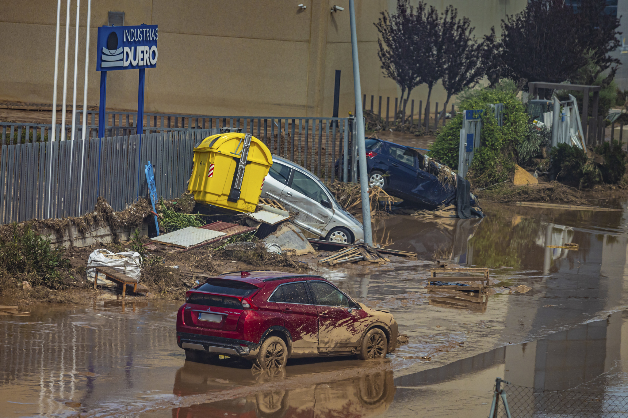Imagen de una calle inundada de Toledo con coches desparramados.