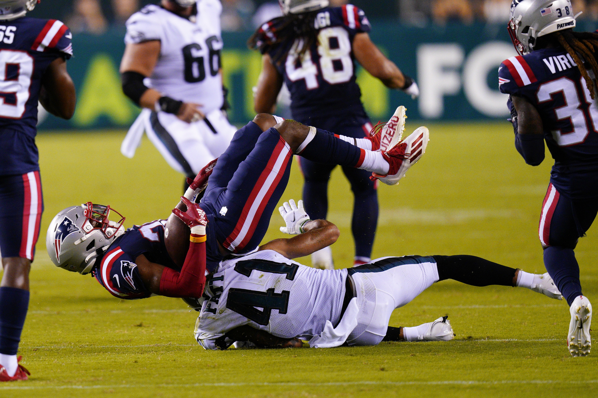 Patriots Adrian Colbert intercepts the ball as he's tackled by Eagles Andre Patton.