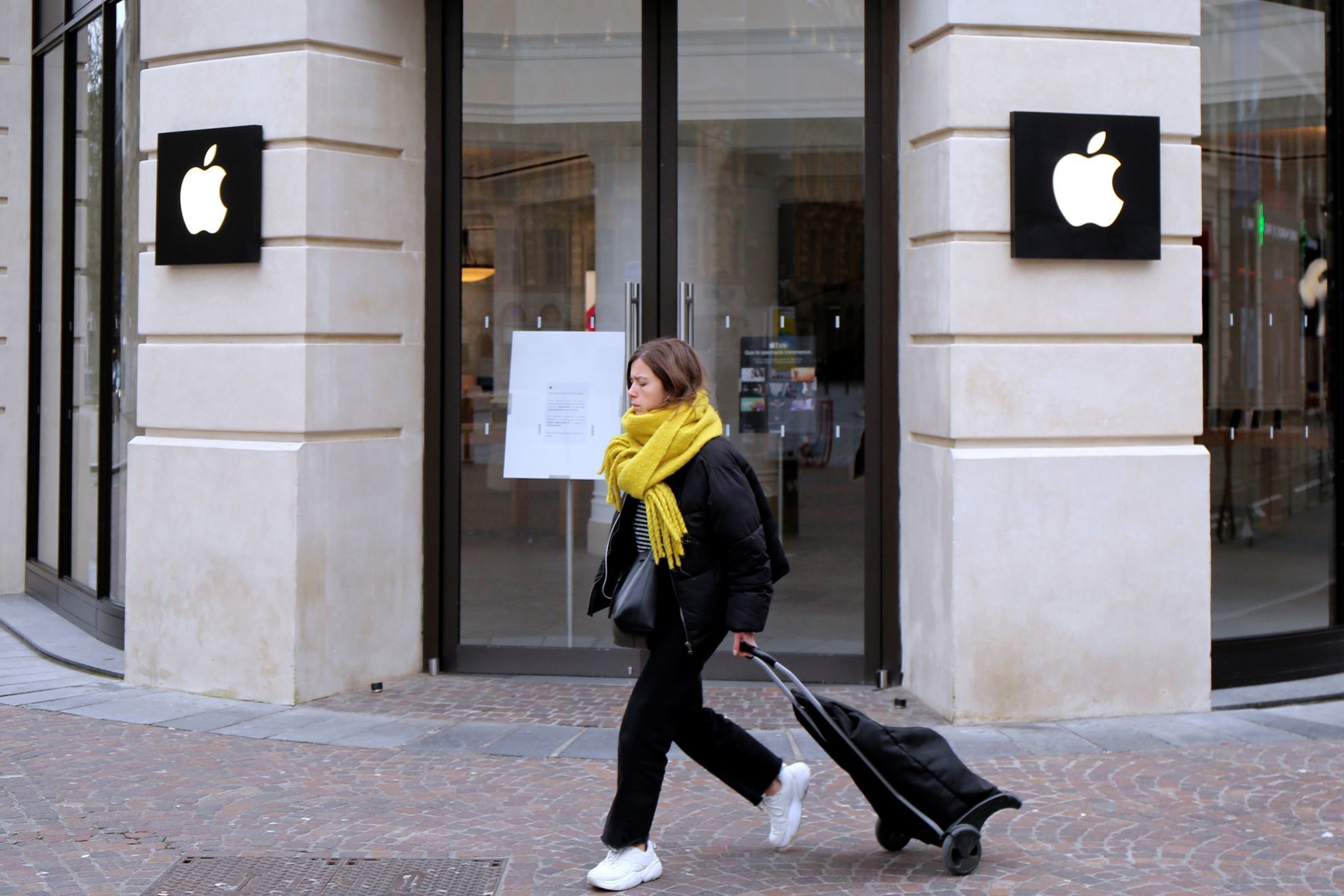 A woman walks past a closed Apple Store in Lille.