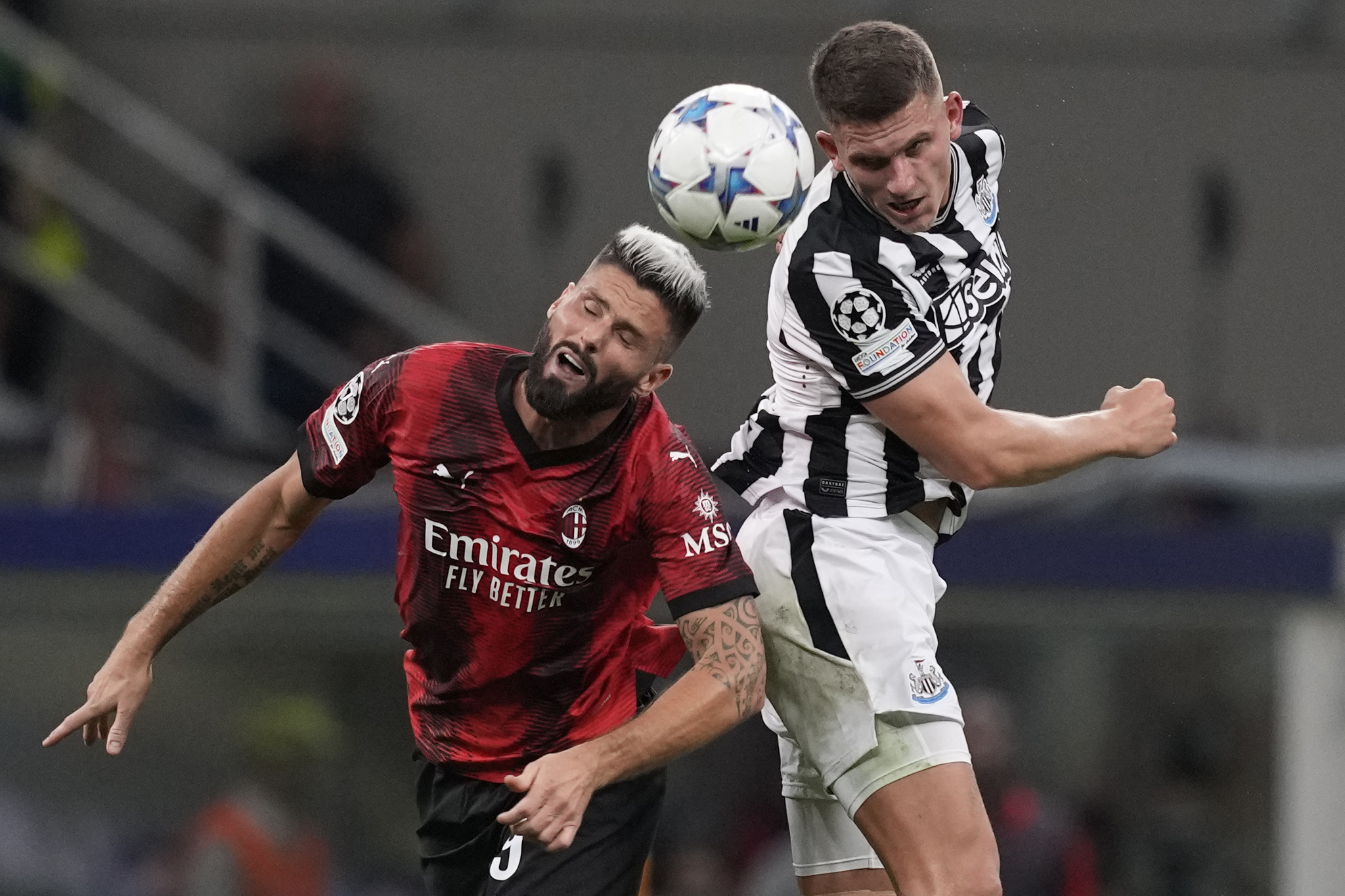 AC Milan's Olivier Giroud, left, goes for the header with Newcastle's Sven Botman