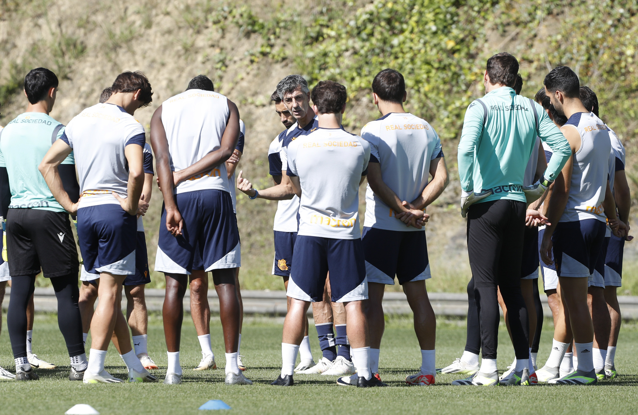 Los jugadores realistas escuchan a Imanol Alguacil antes de iniciar un entrenamiento.