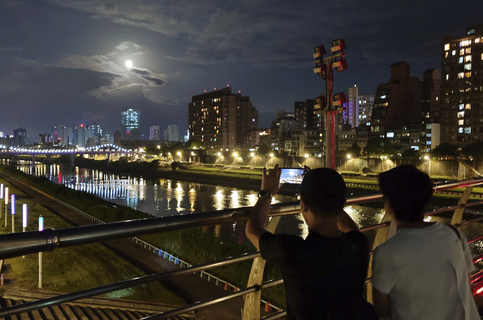 People take pictures with the moon and night scene on the night of the Mid-Autumn Festival in Taipei, Taiwan, Friday, Sept. 29, 2023. (AP Photo/Chiang Ying-ying)