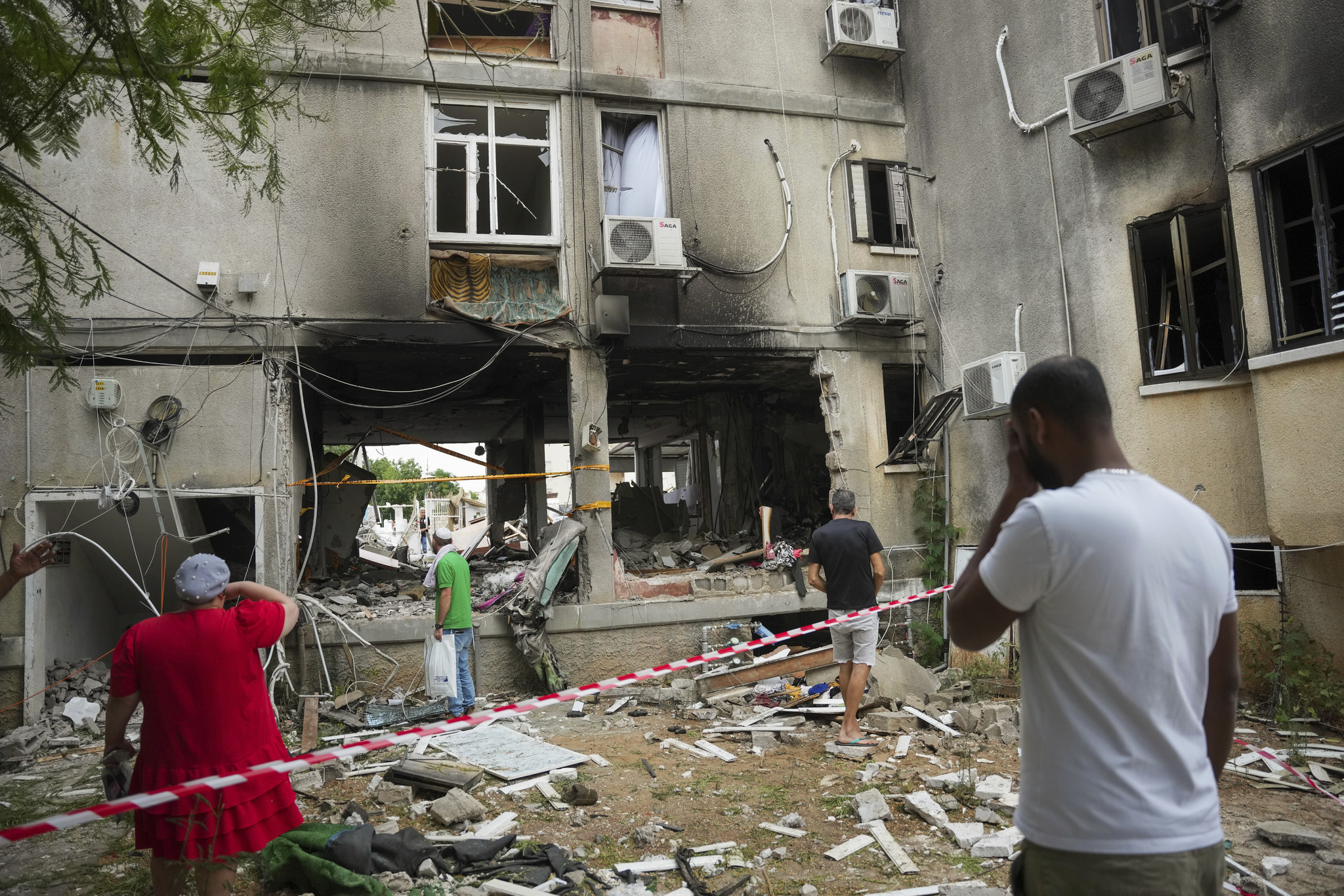 Israelis inspect a damaged residential building after it was hit by a rocket fired from the Gaza Strip, in Ashkelon, Israel.