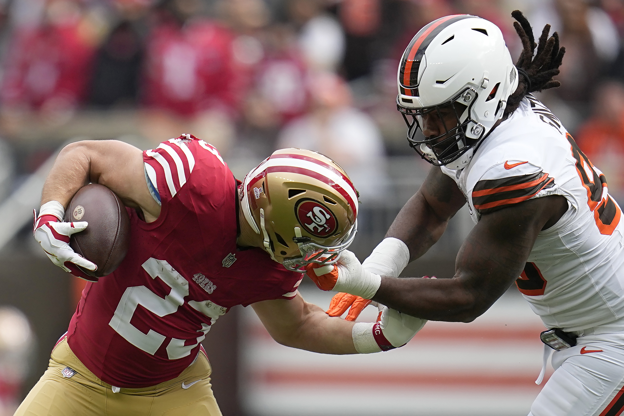 Cleveland Browns defensive end Za'Darius Smith, right, grabs the face mask of San Francisco 49ers running back Christian McCaffrey