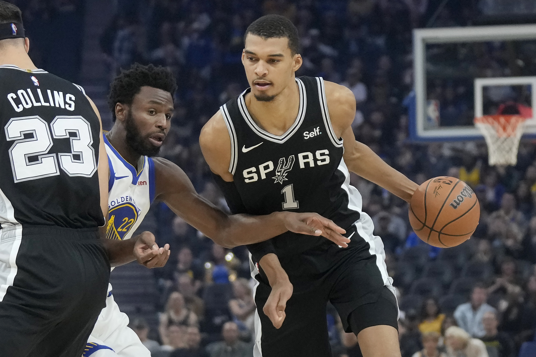 San Antonio Spurs center Victor Wembanyama (1) drives to the basket against Golden State Warriors forward Andrew Wiggins during the first half of an NBA preseason basketball game in San Francisco, Friday, Oct. 20, 2023. (AP Photo/Jeff Chiu)
