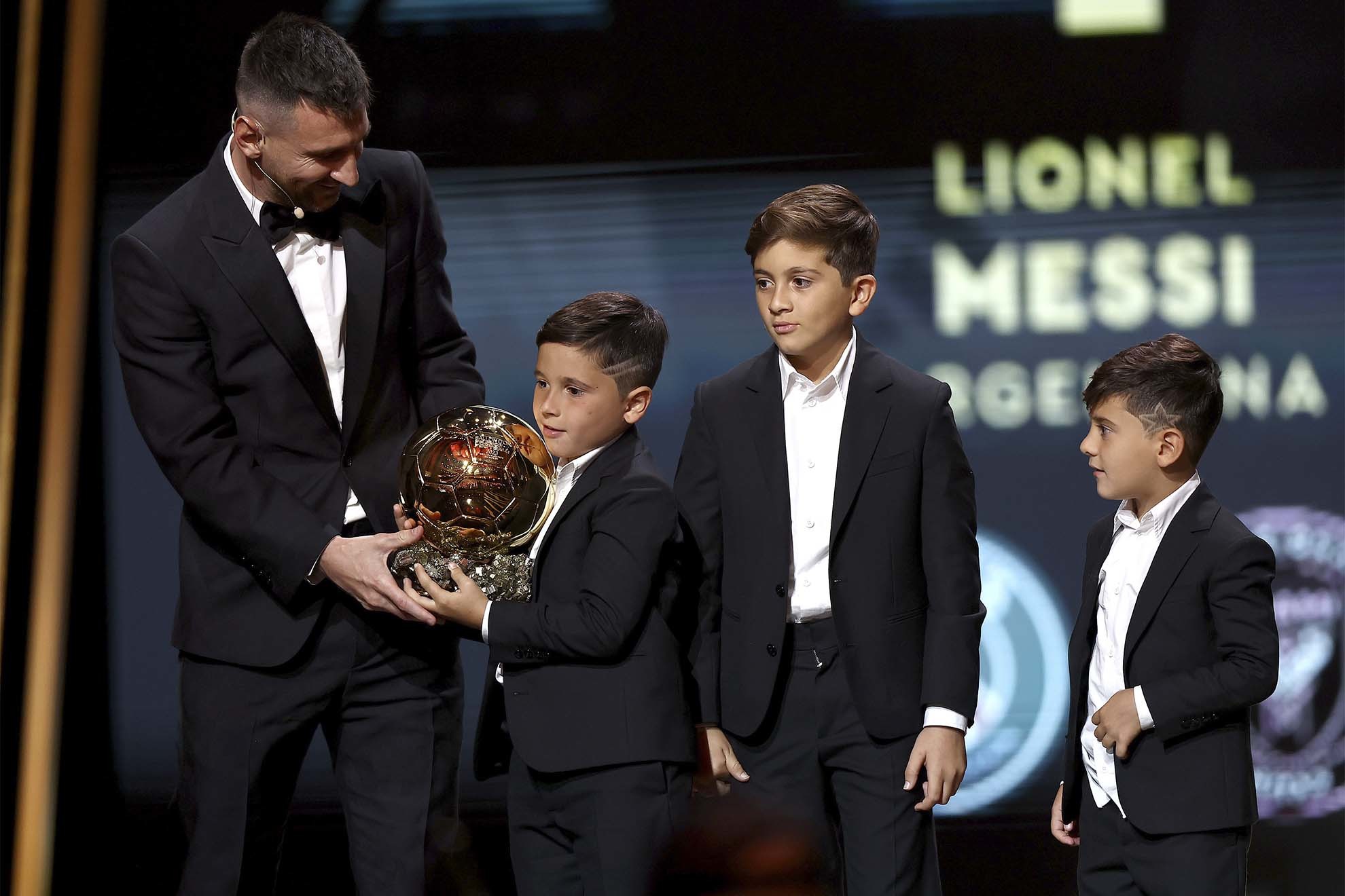 Leo Messi ayuda a uno de sus hijos a sujetar el Balón de Oro durante la Gala del lunes.