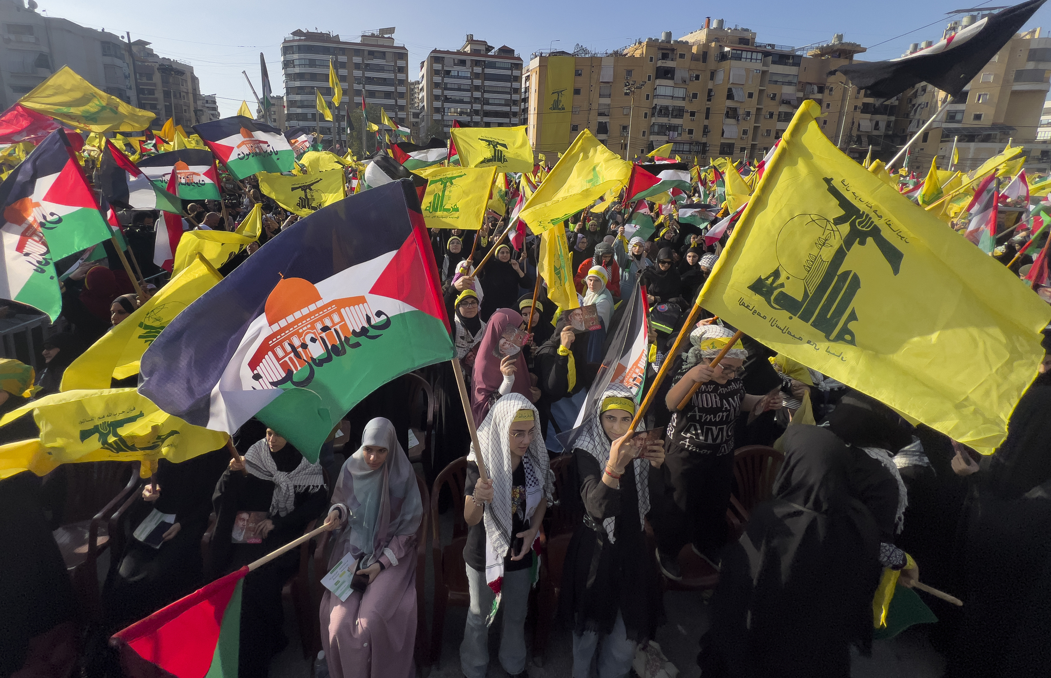 Supporters of the Iranian-backed Hezbollah group wave Palestinian and their group flags