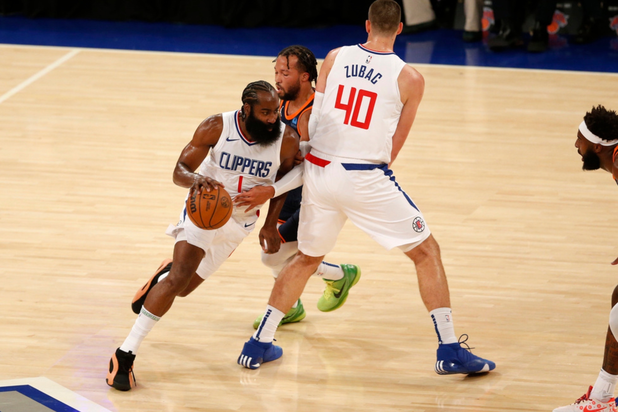 Los Angeles Clippers guard James Harden dribbles around teammate Ivica Zubac (40) and New York Knicks guard Jalen Brunson during the first half of an NBA basketball game