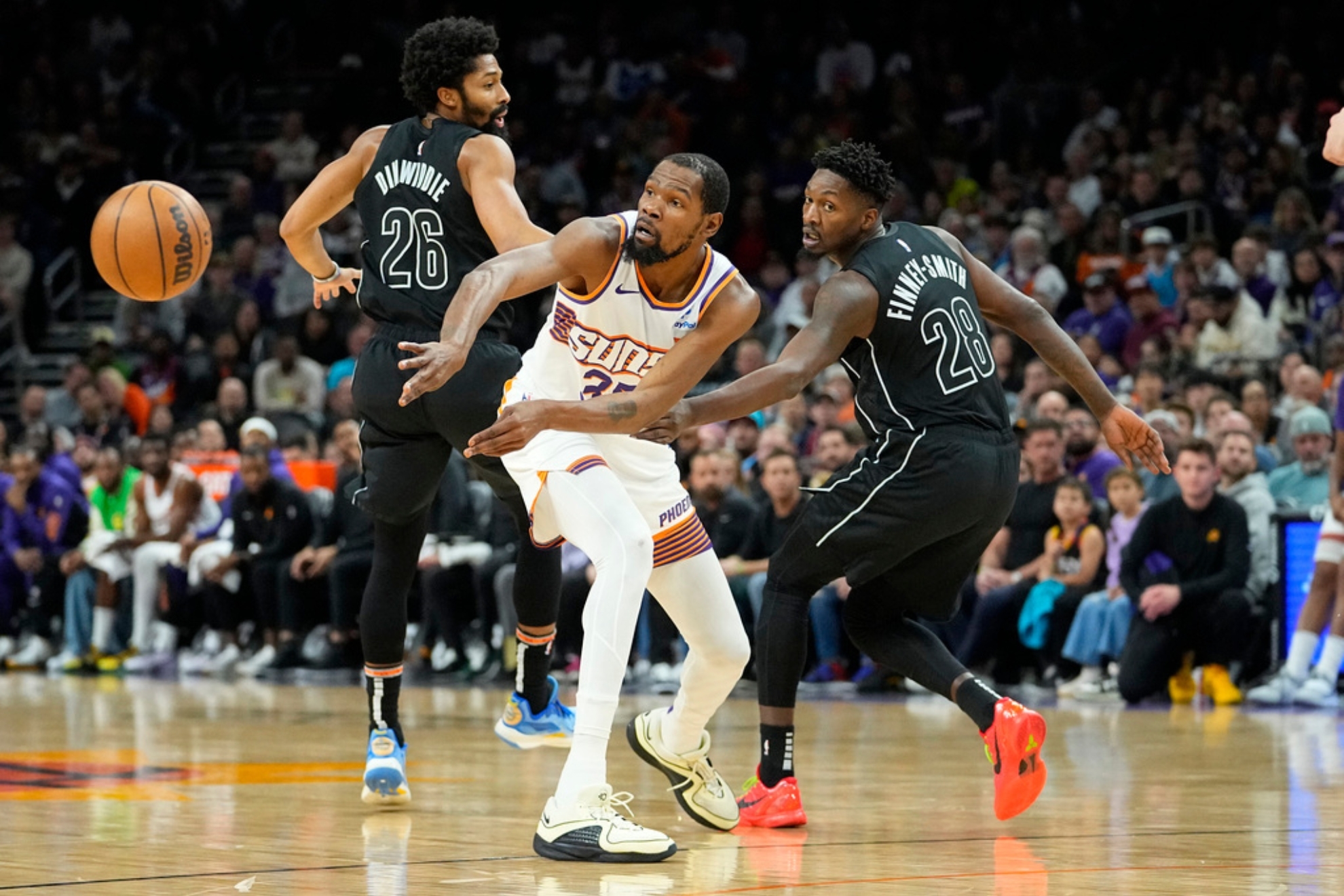 Phoenix Suns forward Kevin Durant (35) passes between Brooklyn Nets forward Dorian Finney-Smith (28) and guard Spencer Dinwiddie (26) during the first half of an NBA basketball game, Wednesday, Dec. 13, 2023, in Phoenix. (AP Photo/Matt York)