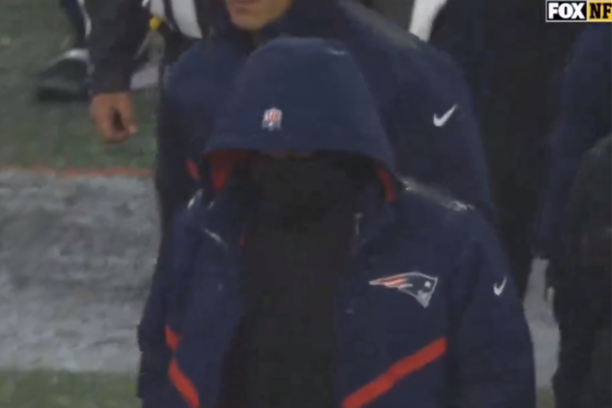 Belichicks face is obscured from view as he walks toward Jets coach Robert Saleh.