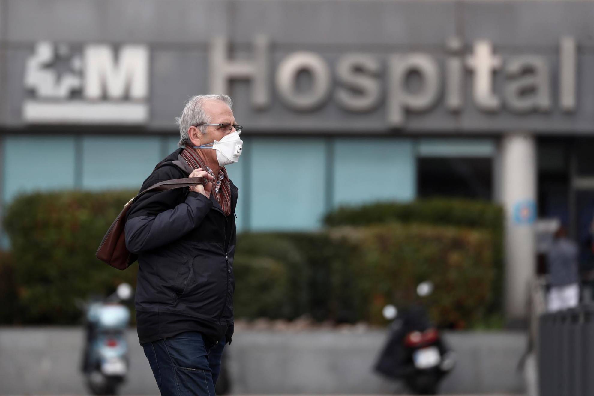 Un hombre usando mascarilla a las puertas de un hospital.