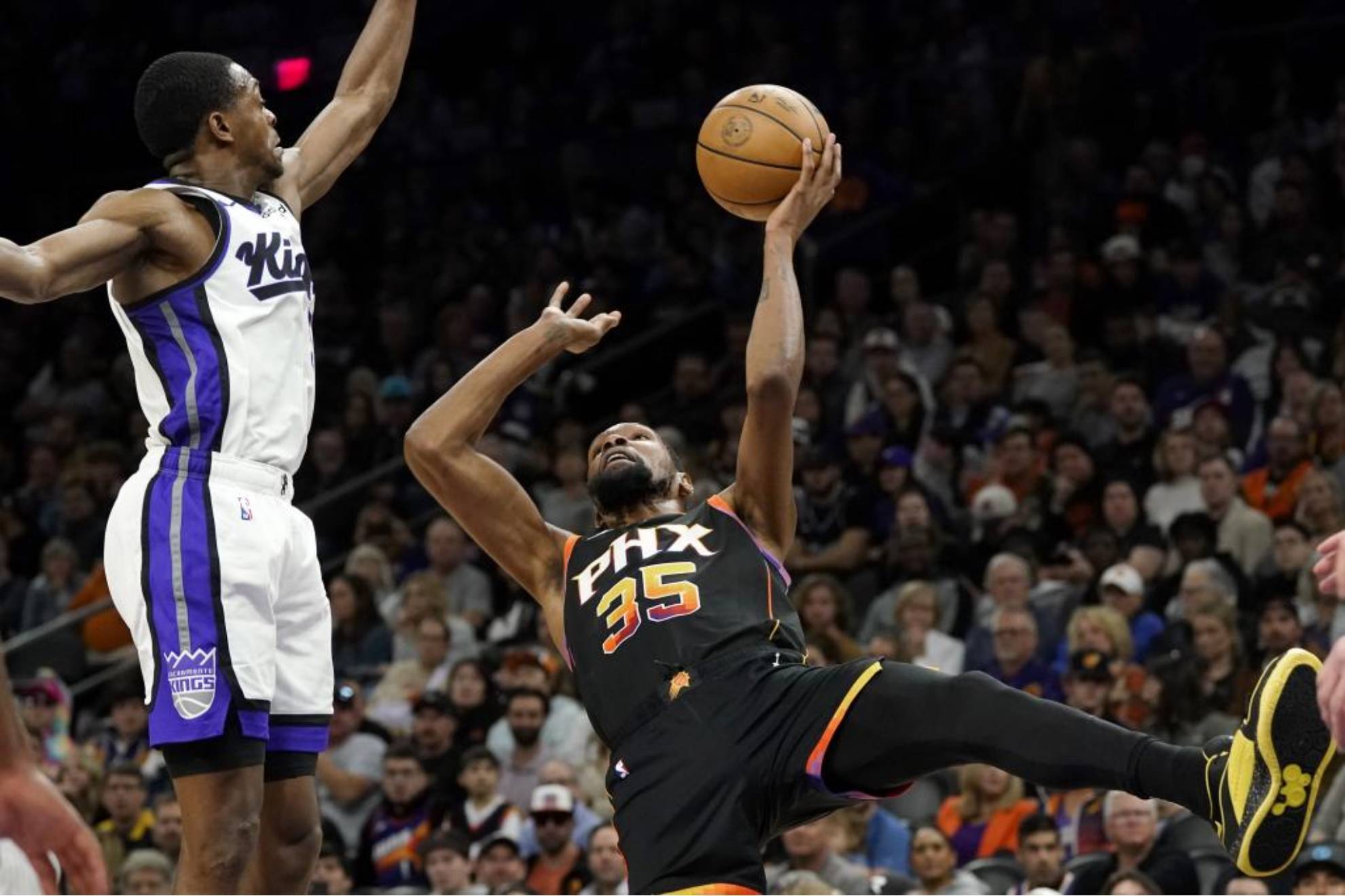 Kevin Durant lanza cayéndose al suelo ante DeAaron Fox durante el Suns-Kings.