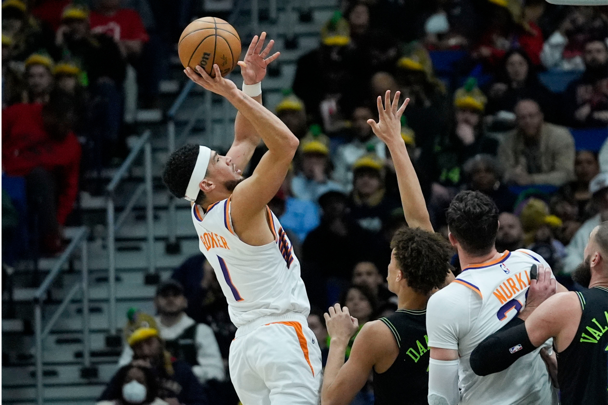Phoenix Suns guard Devin Booker (1) shoots against New Orleans Pelicans guard Dyson Daniels, second from left, in the first half of an NBA basketball game in New Orleans, Friday, Jan. 19, 2024.