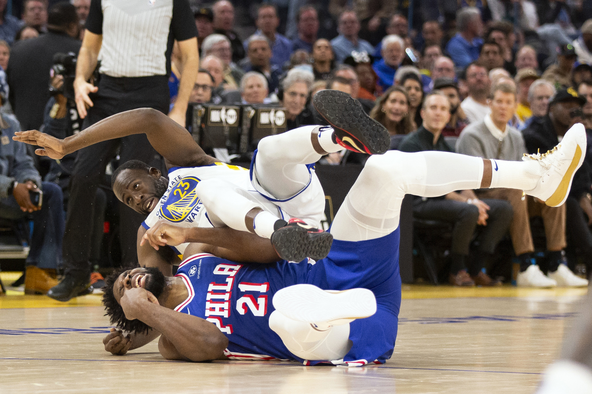 Joel Embiid falls to the ground with Draymond Green