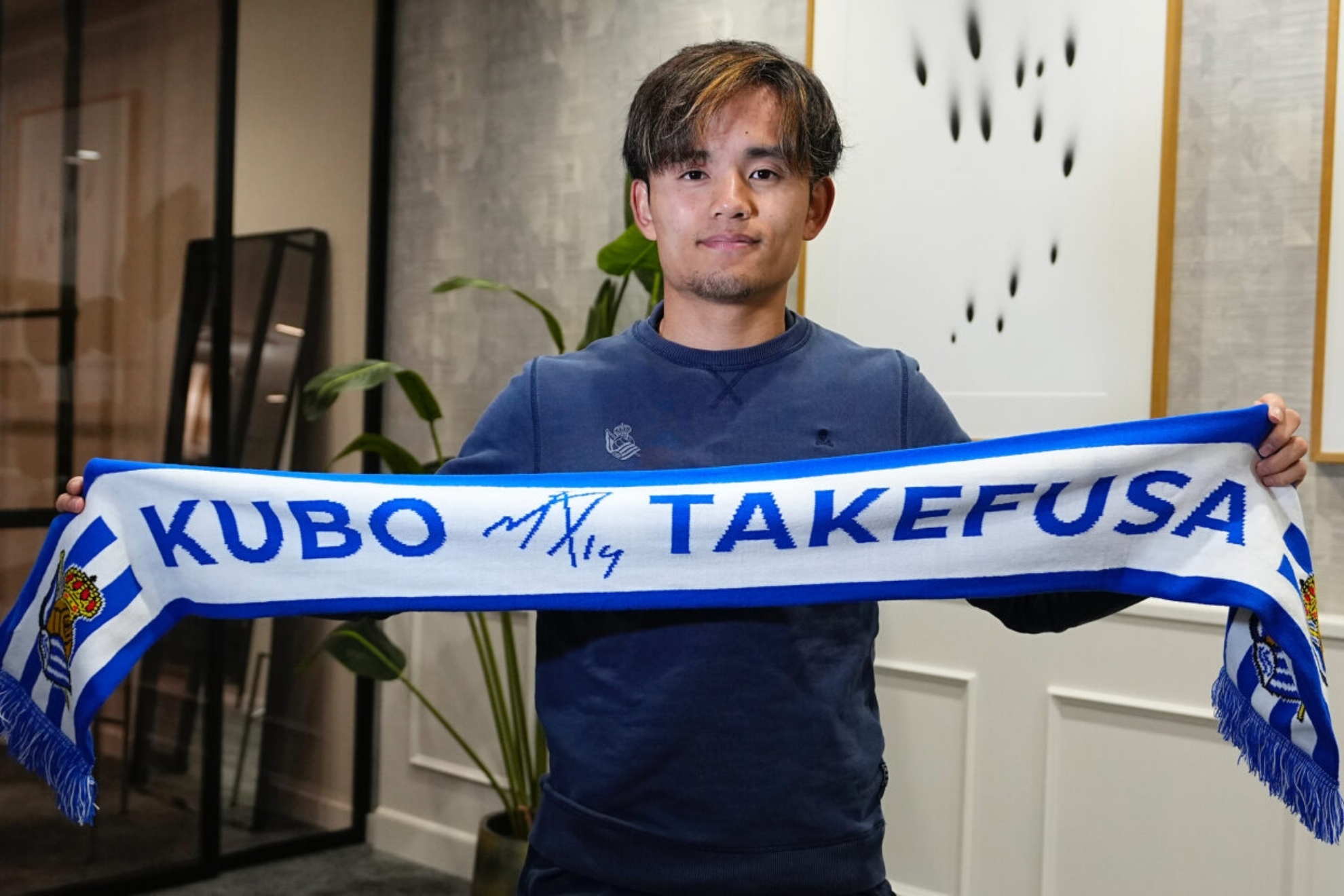 Take Kubo posa con su bufanda personal de la Real Sociedad.