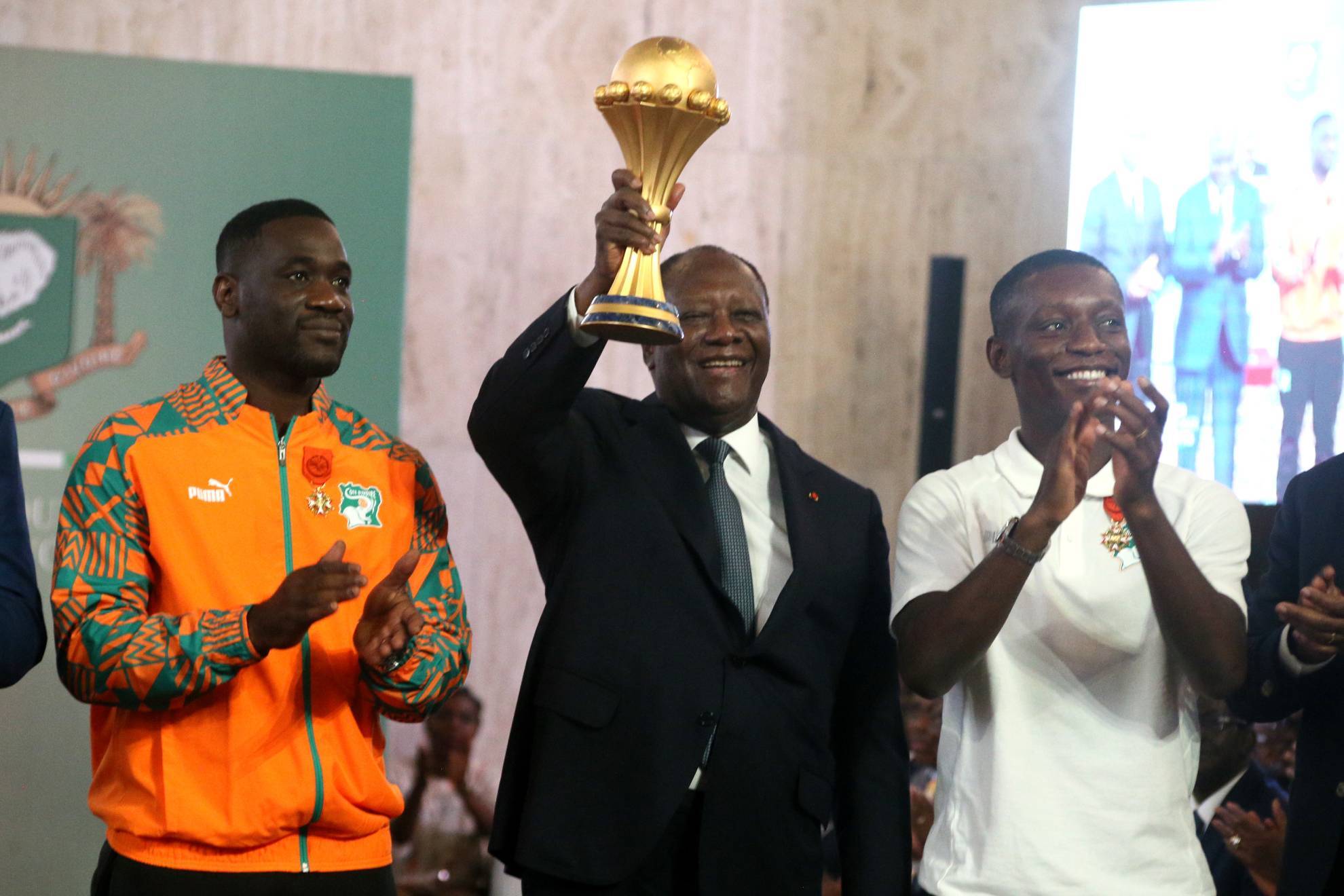 Alassane Outtara, presidente de Costa de Marfil, sostiene el trofeo al lado del seleccionador Emerse Fae (izquierda) y el capitán Max Gradel (derecha)