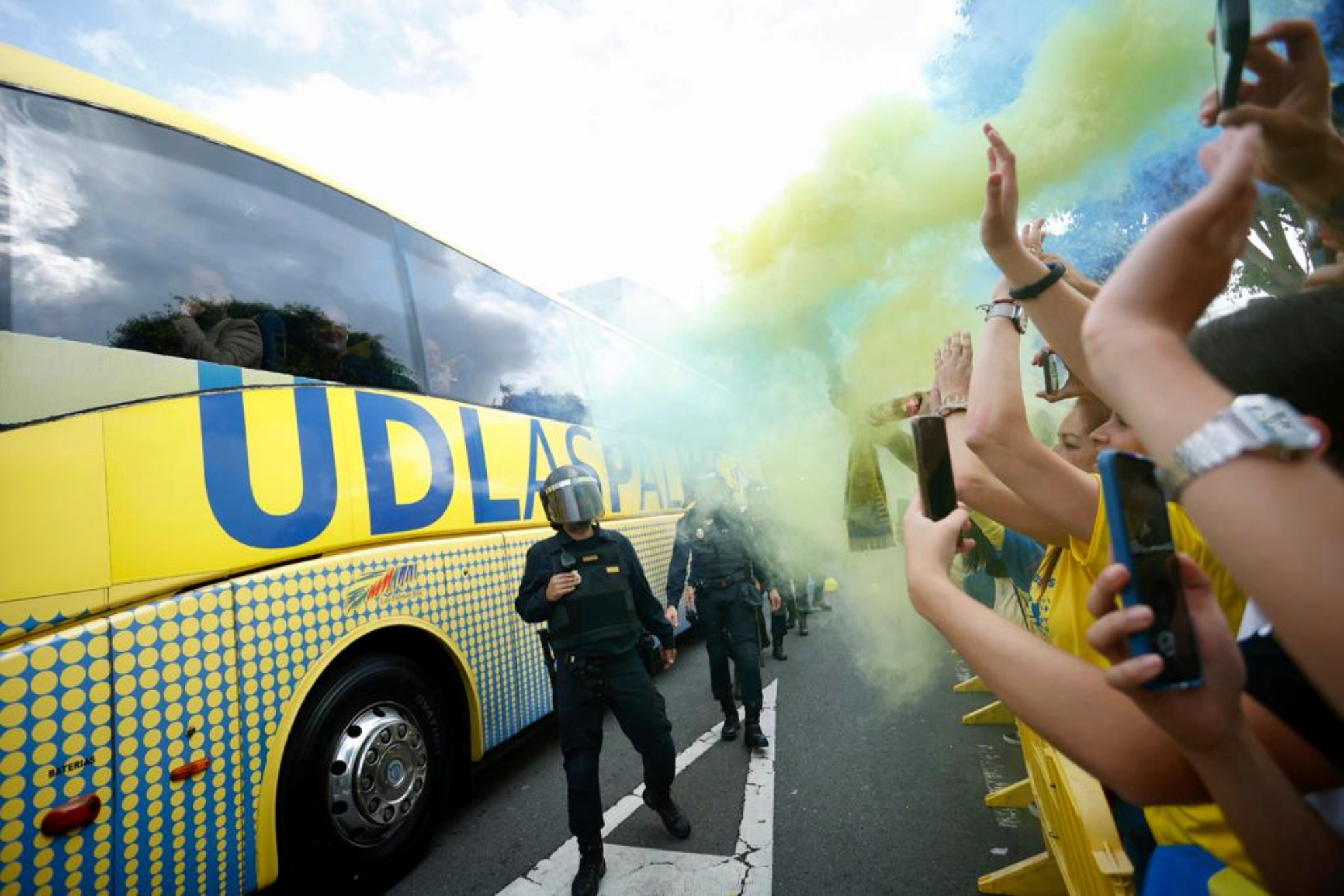 La afición de Las Palmas recibe al autobús de su equipo con bengalas.