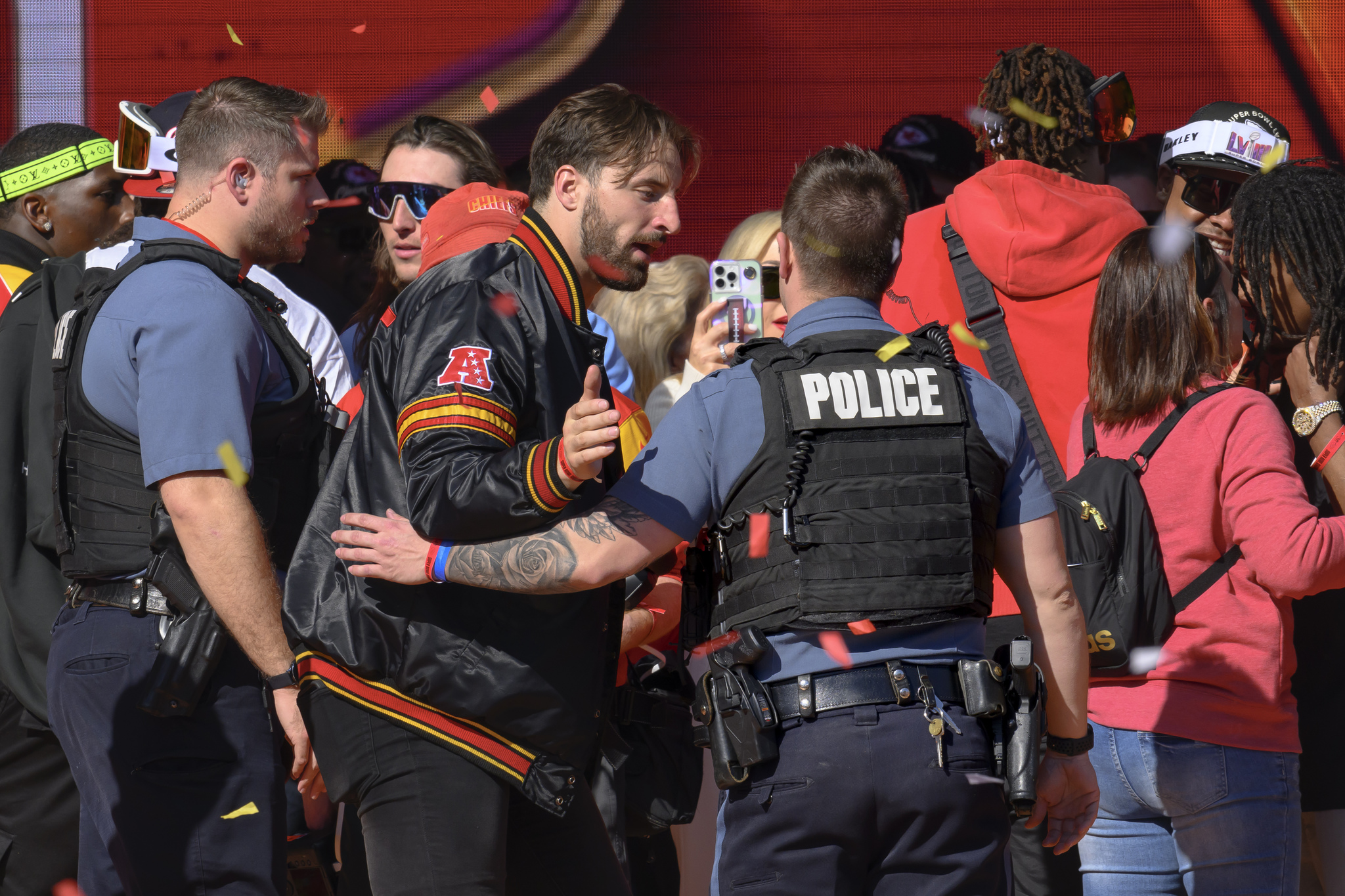 Police escort Kansas City Chiefs tight end Noah Gray and his teammates off the stage after shooting