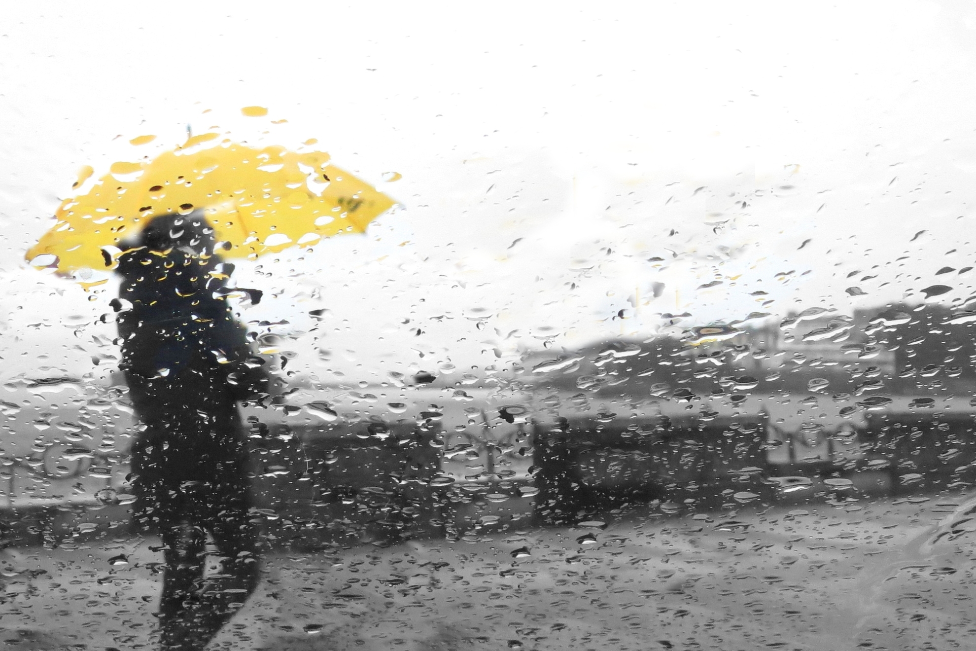 Una persona sujeta un paraguas amarillo durante la lluvia.