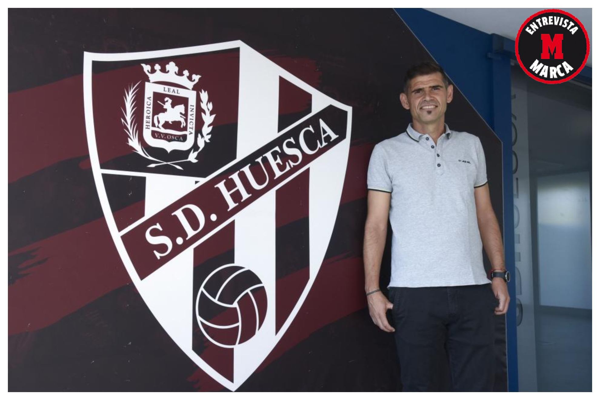 Un sonriente Antonio Hidalgo posa delante del escudo del Huesca