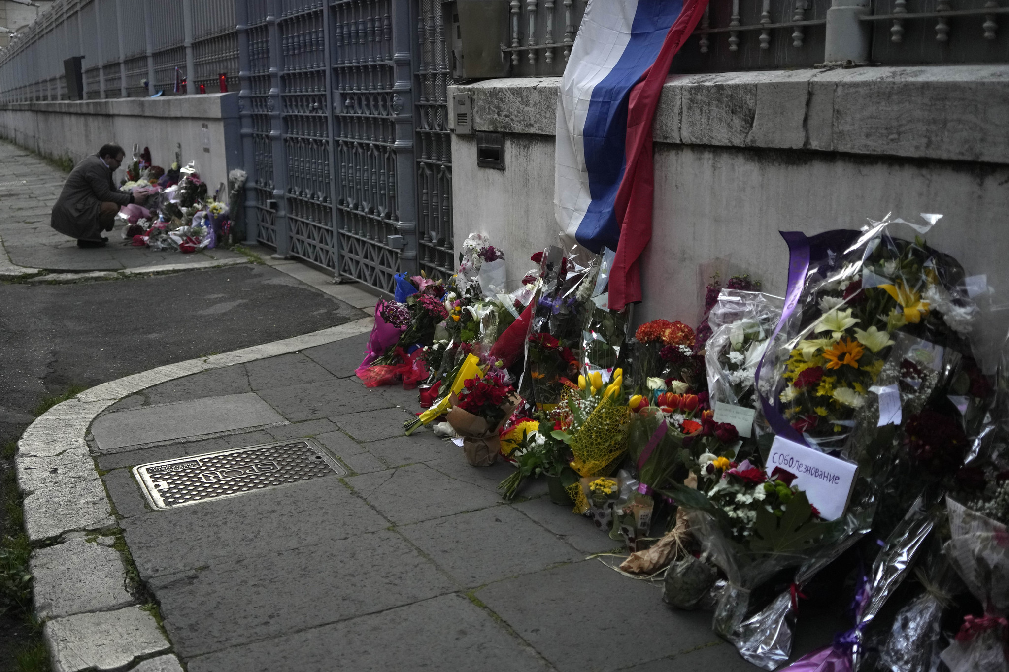 A man looks at flower tributes outside of the Russian embassy in Rome