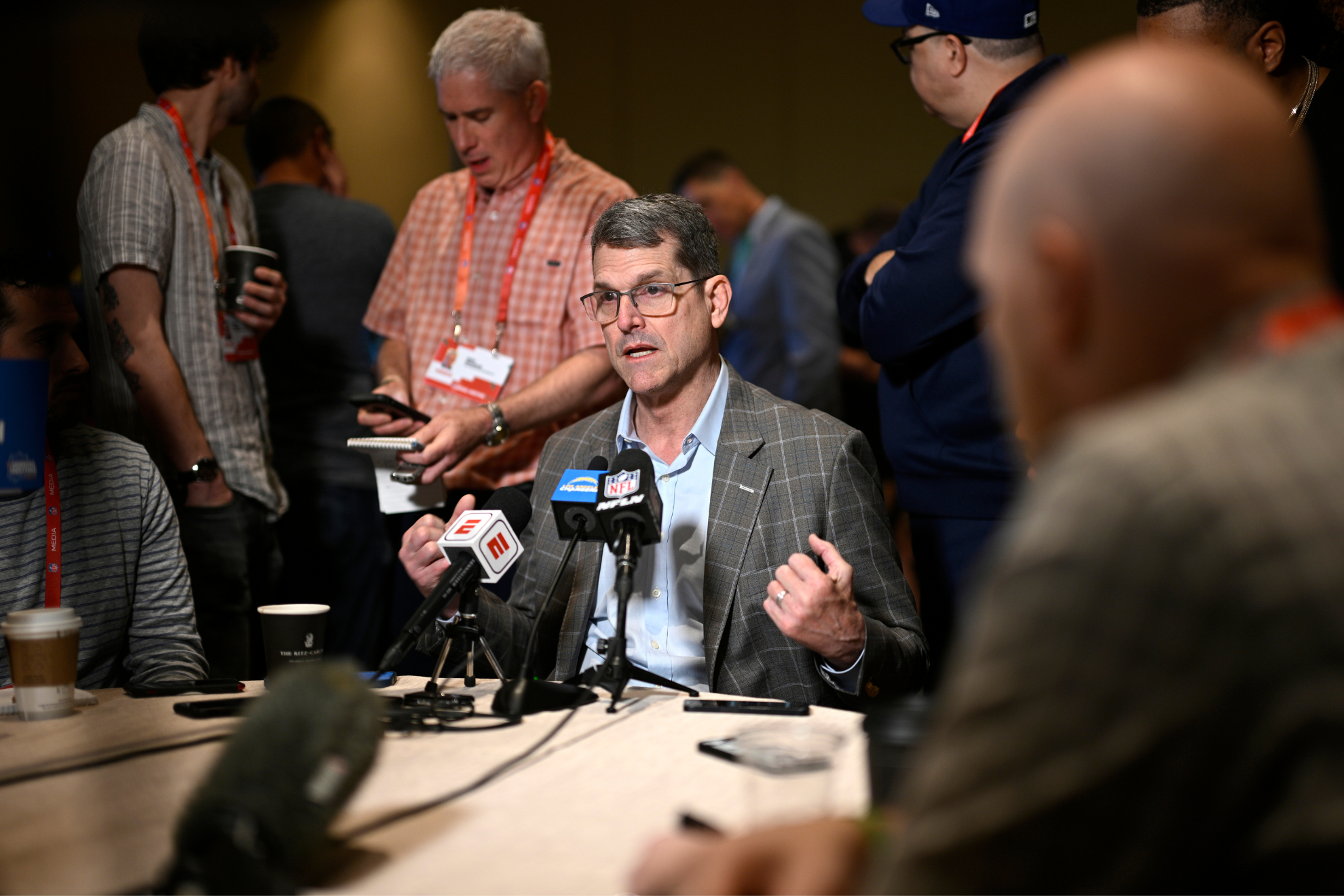 Harbaugh (center, speaking) at the NFL Owners Meetings on Monday.