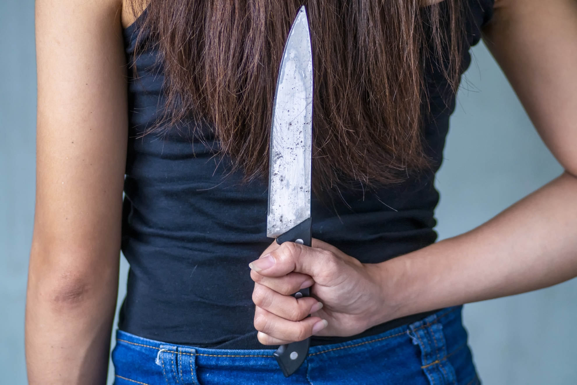 A woman hides a knife behind her back.