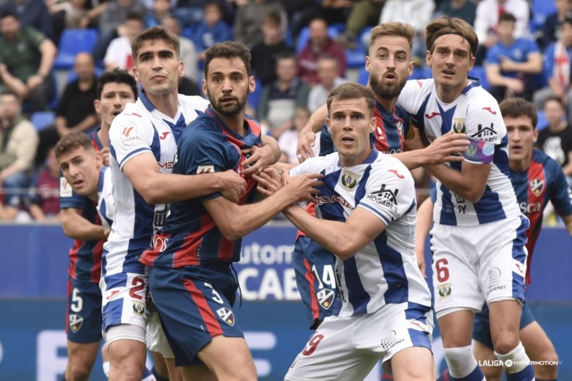 Los jugadores de Huesca y Legans se agarran en un momento del encuentro.